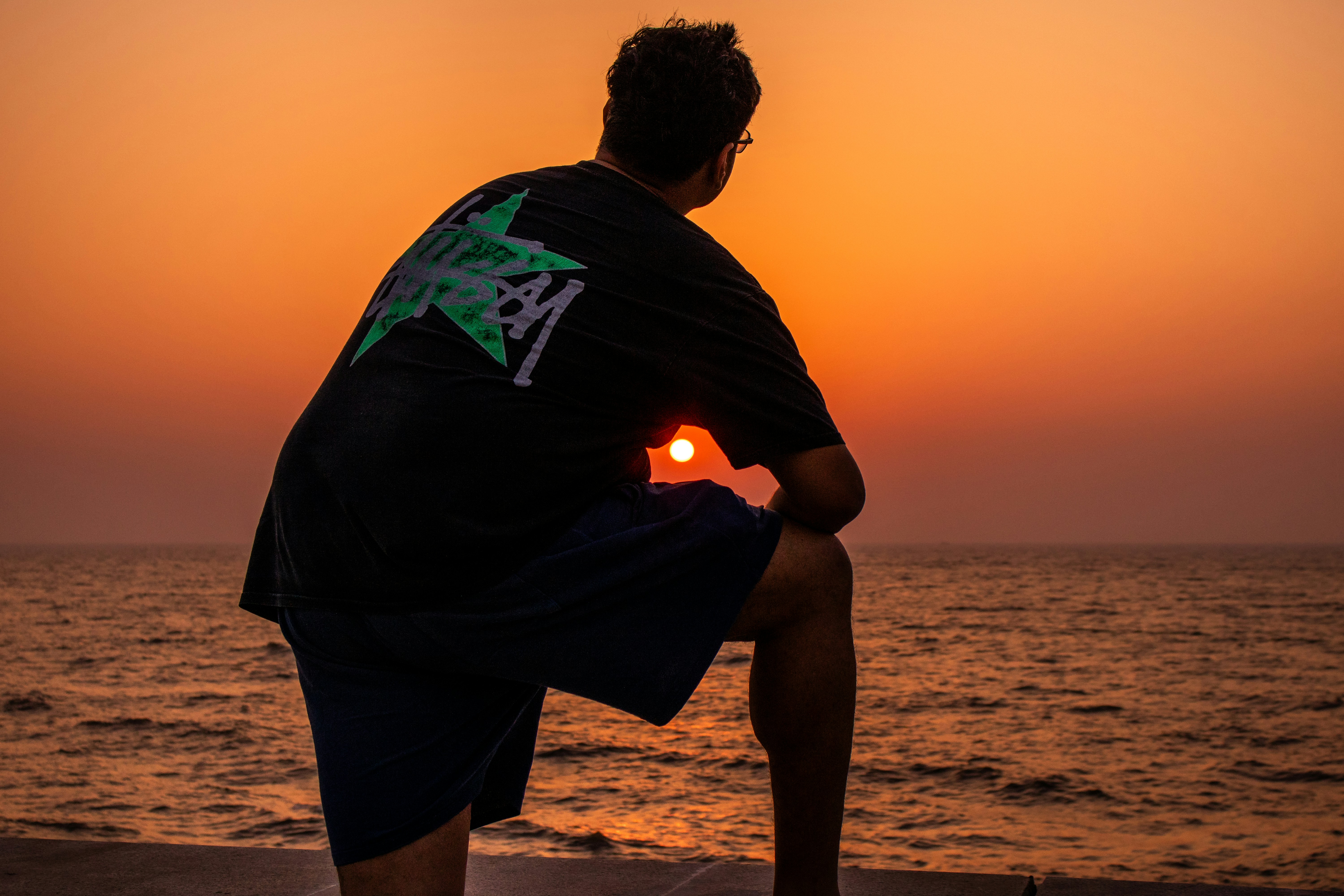 Man watches the sunset over the ocean.