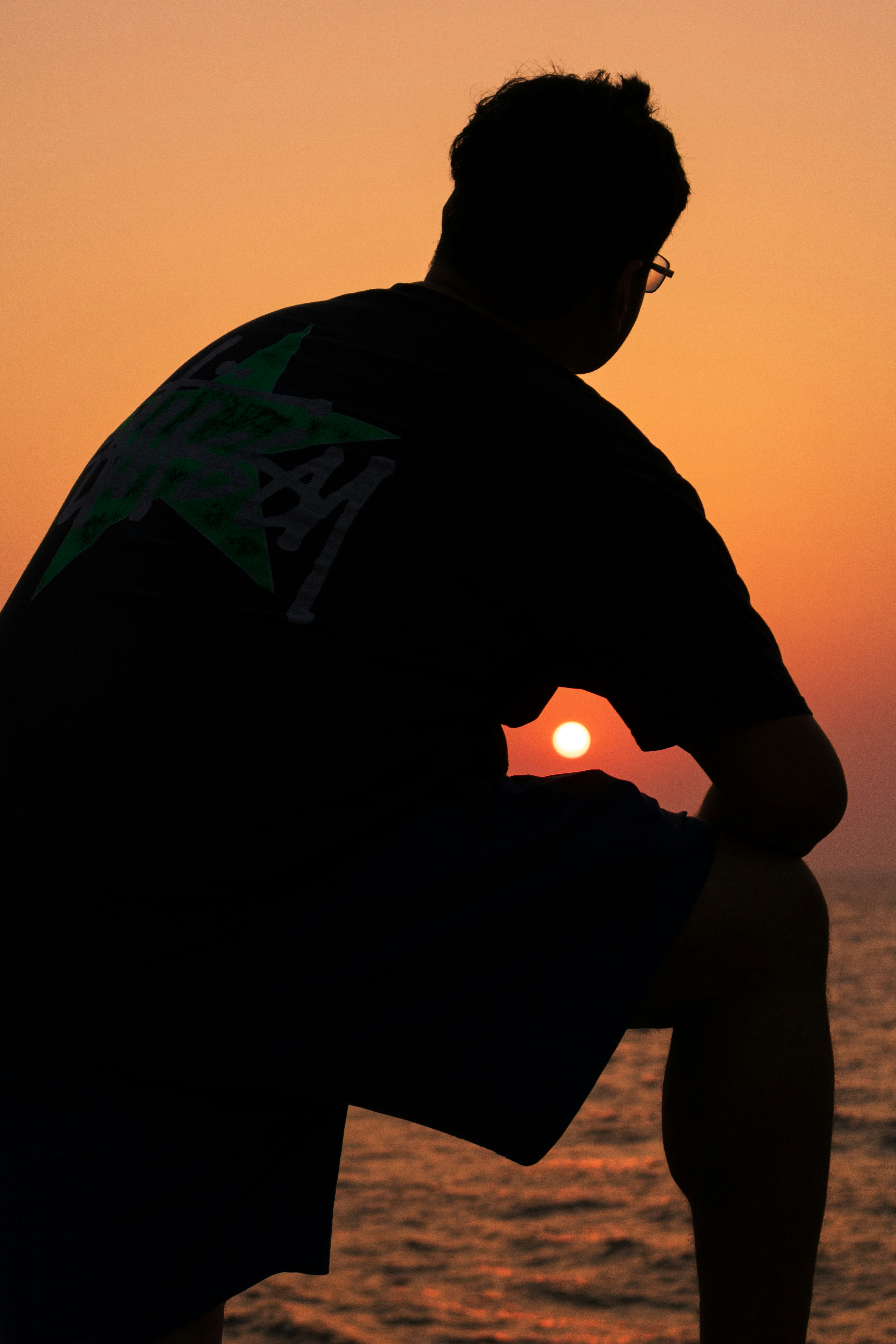 Silhouette of a person watching the sunset over the ocean