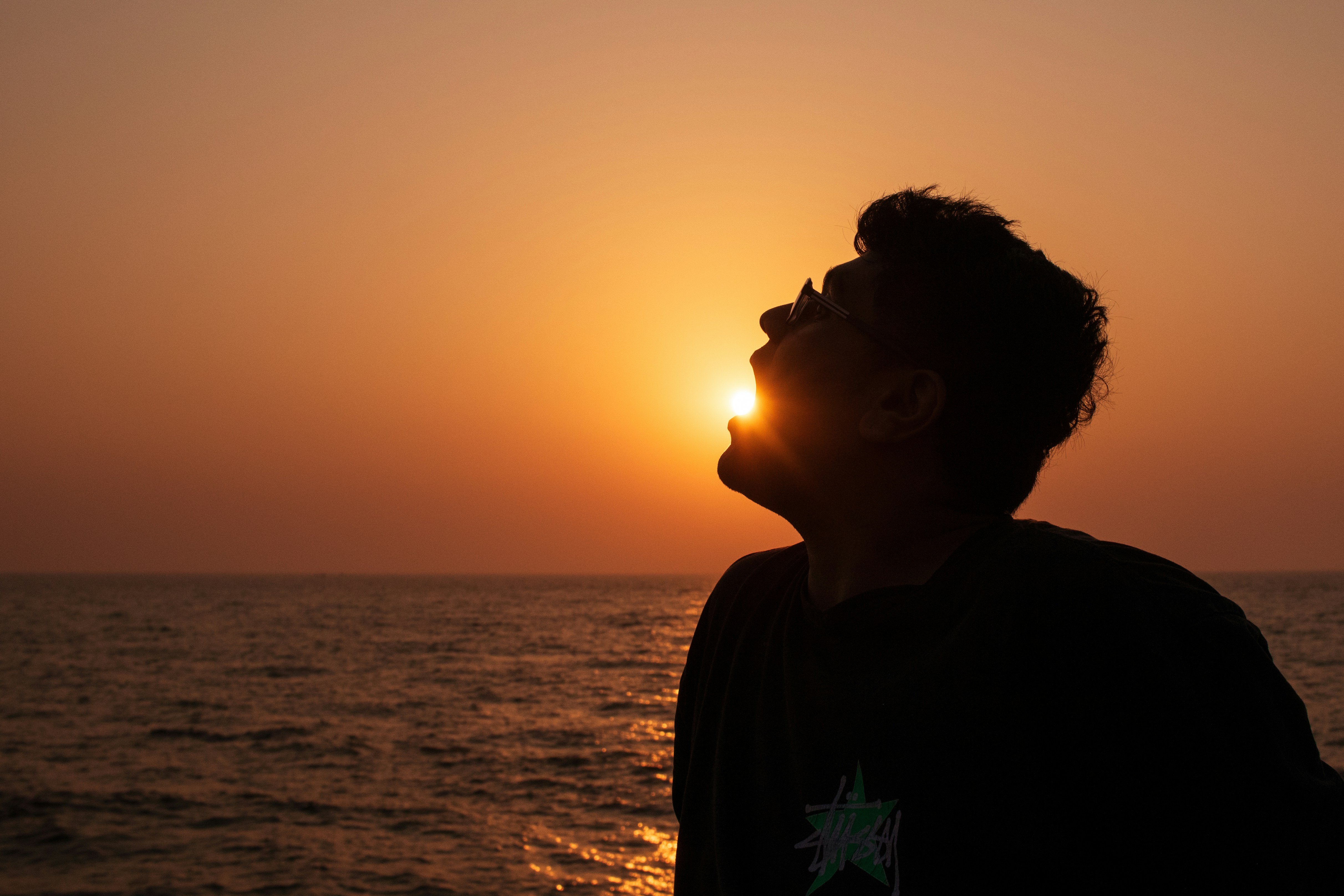 Silhouette of a man with sun setting over the ocean