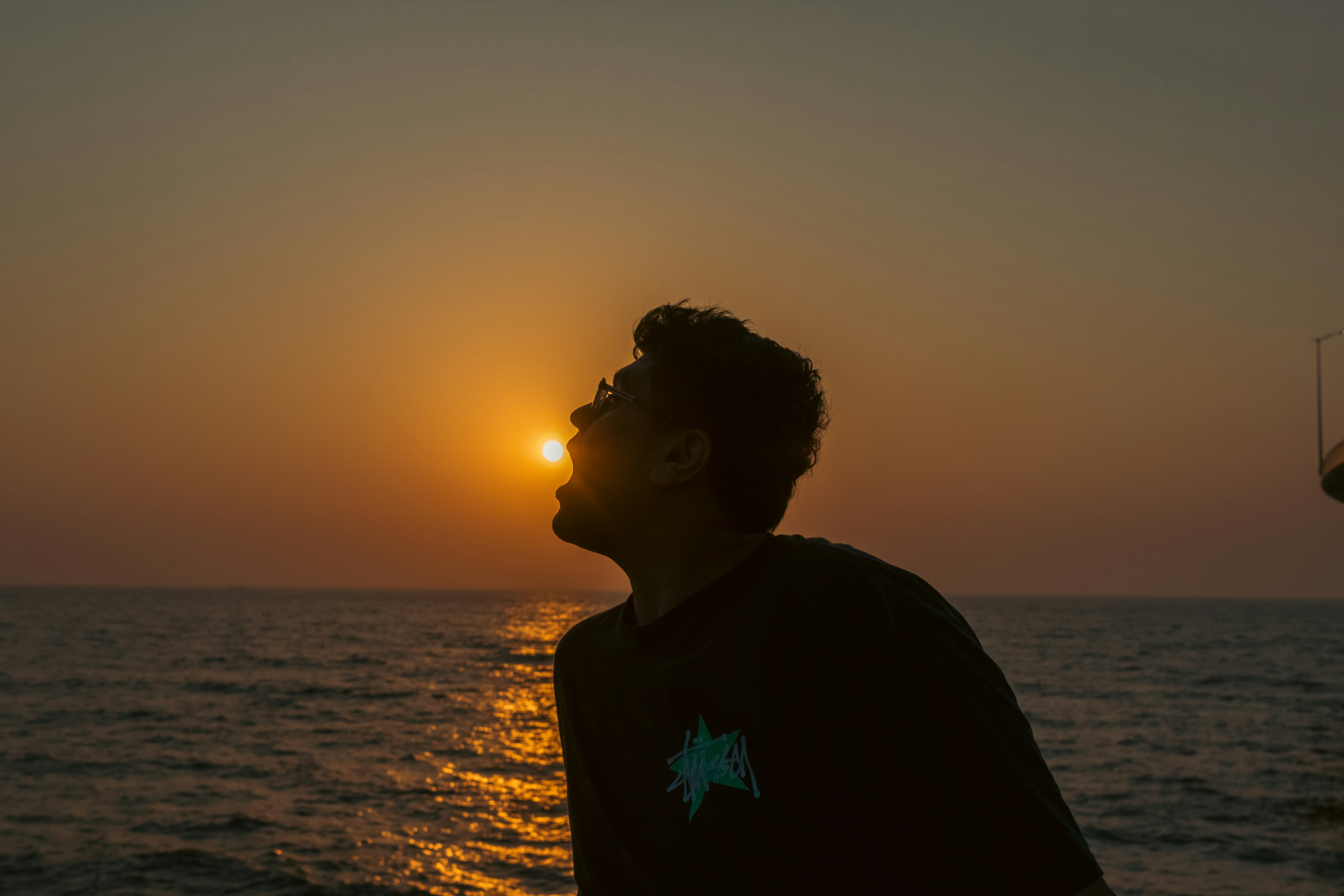 Man looking up at the sun during sunset over ocean
