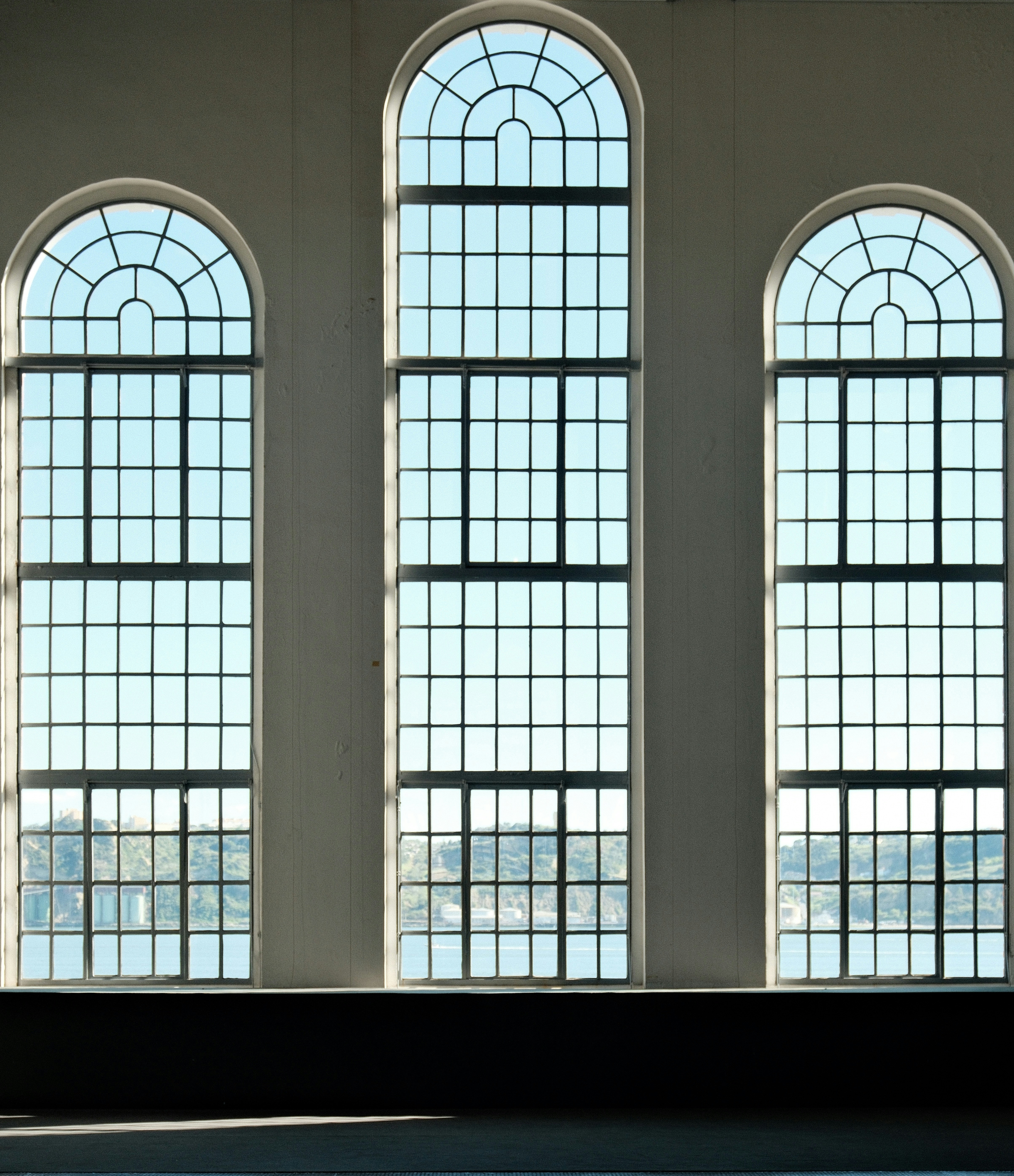 Three arched windows overlook a body of water.