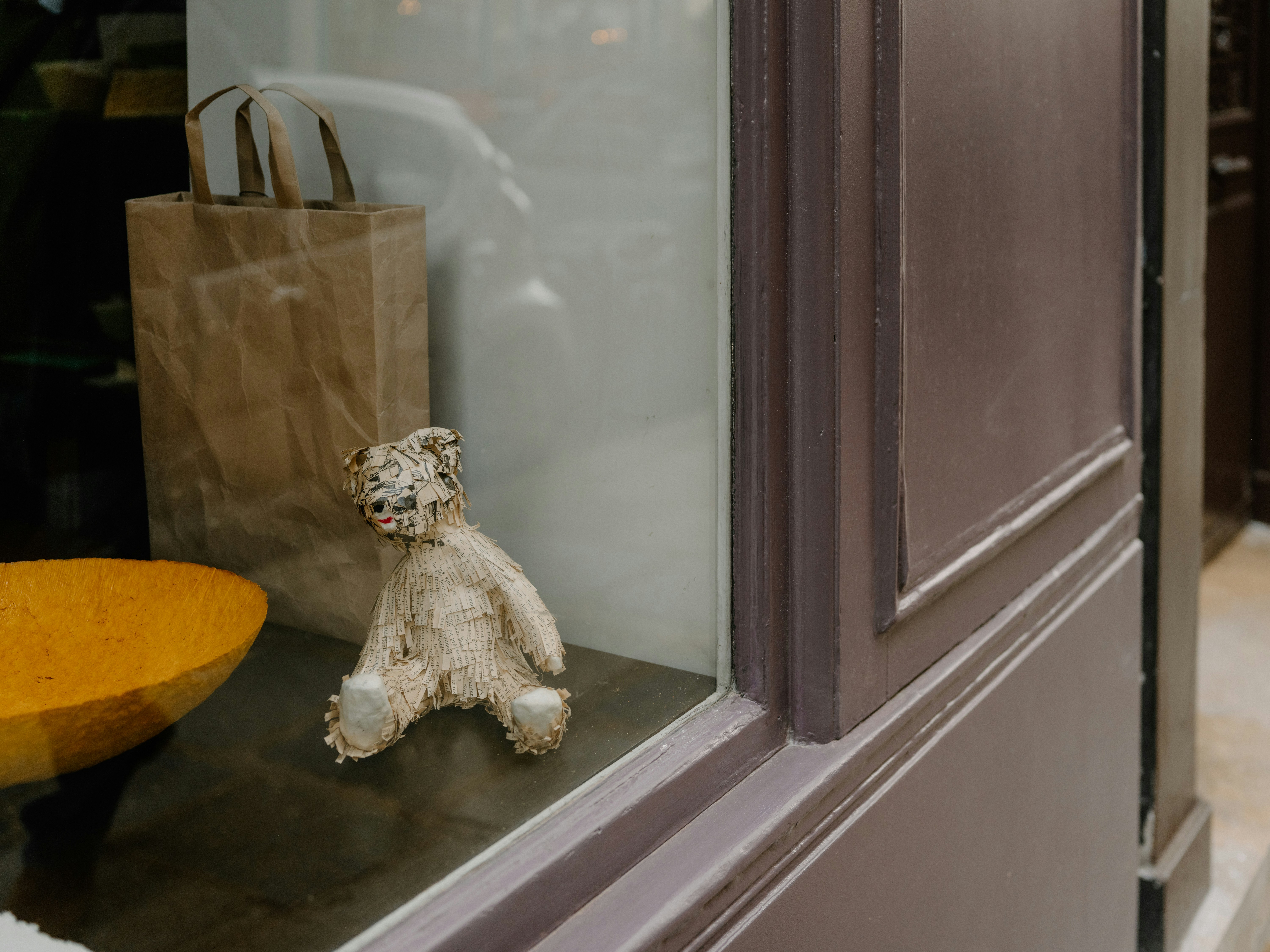 A small teddy bear sits in a shop window display.