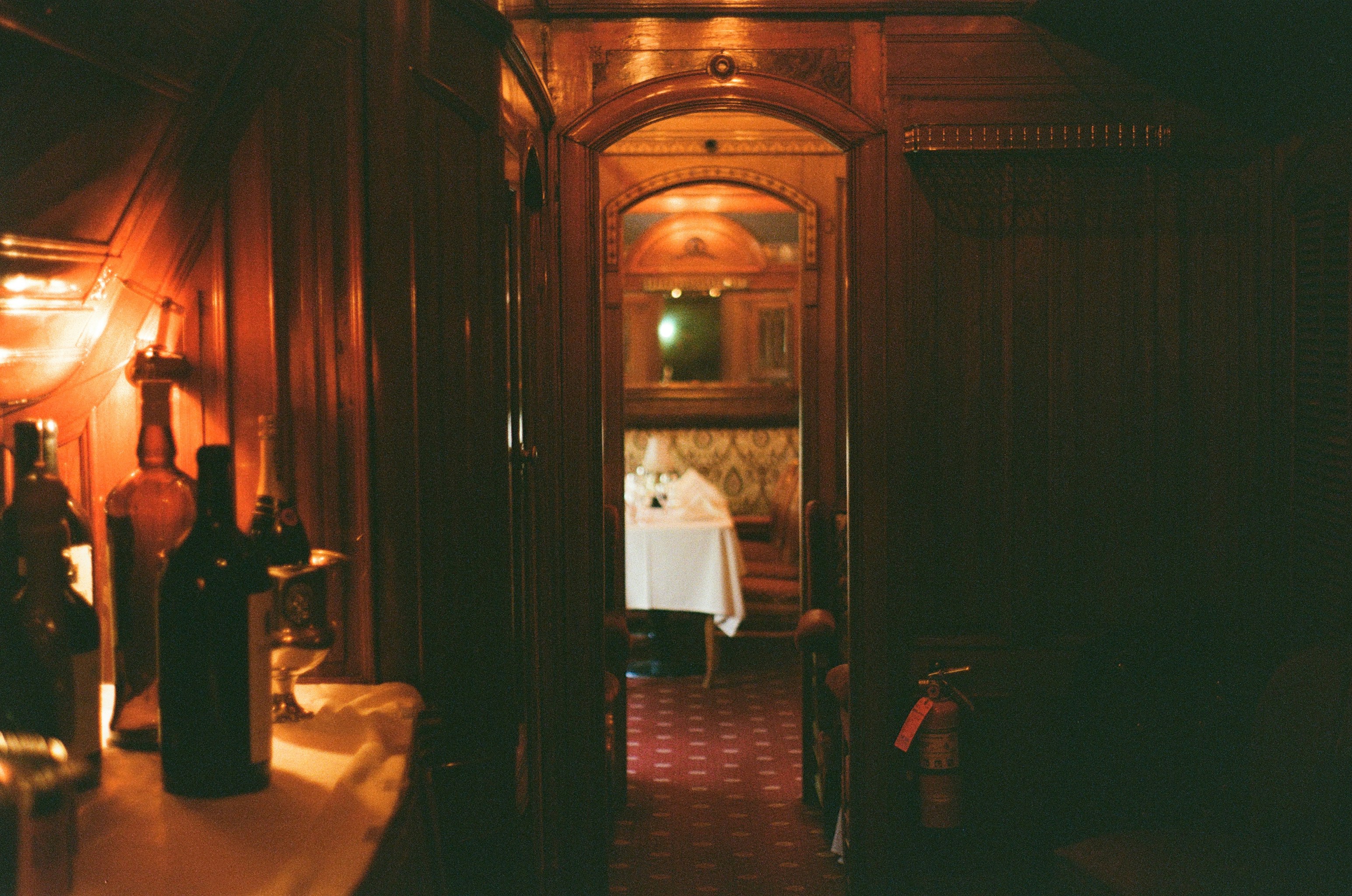 Dark, ornate hallway with bottles and a table.