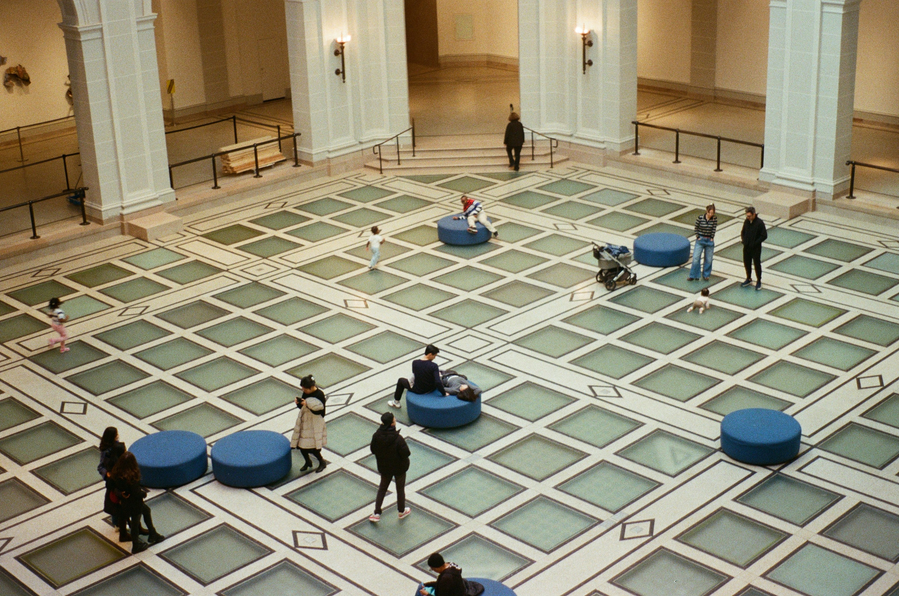 People in a large museum hall with patterned floor.