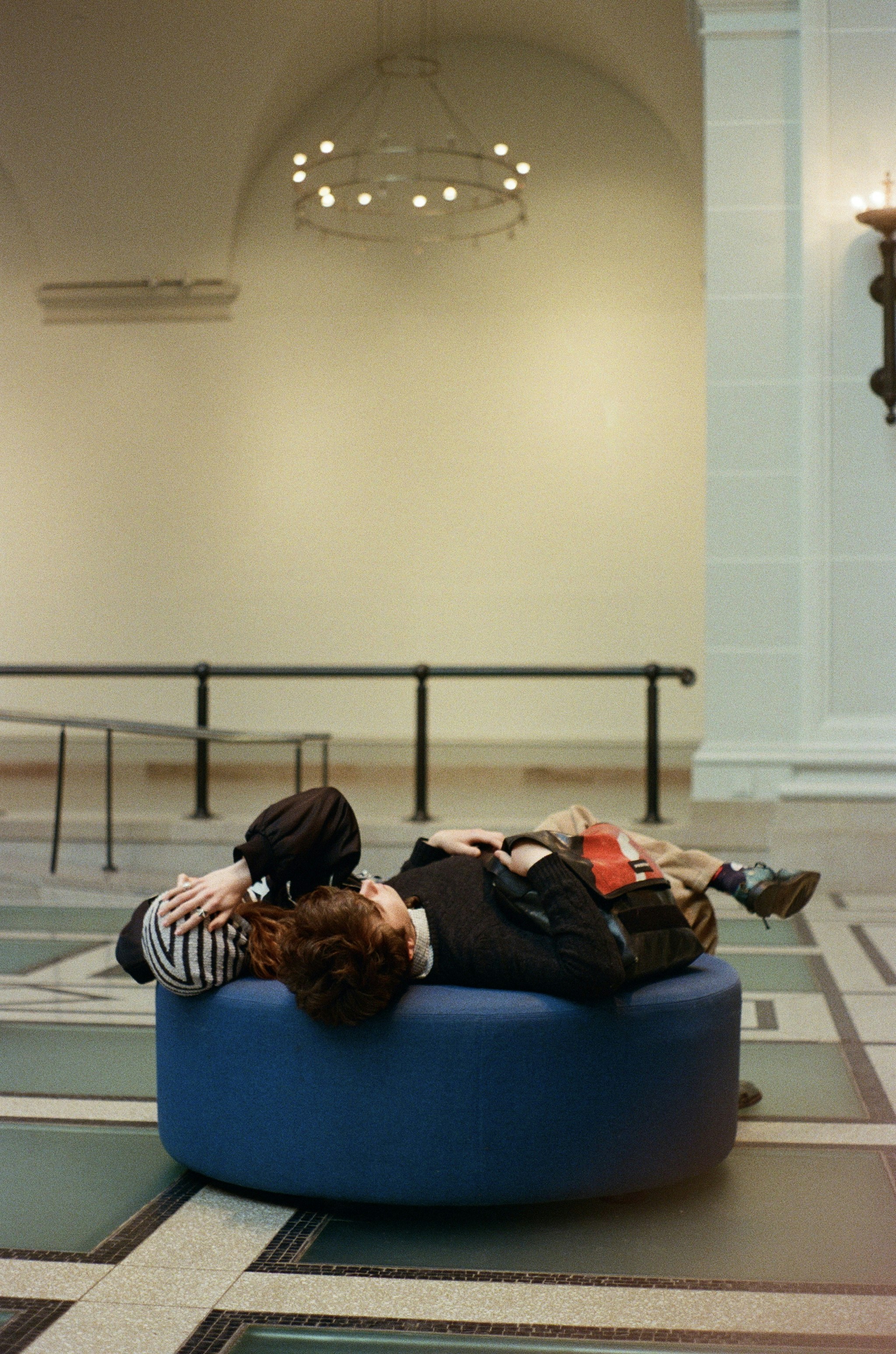 Person resting on a blue ottoman in a large room.