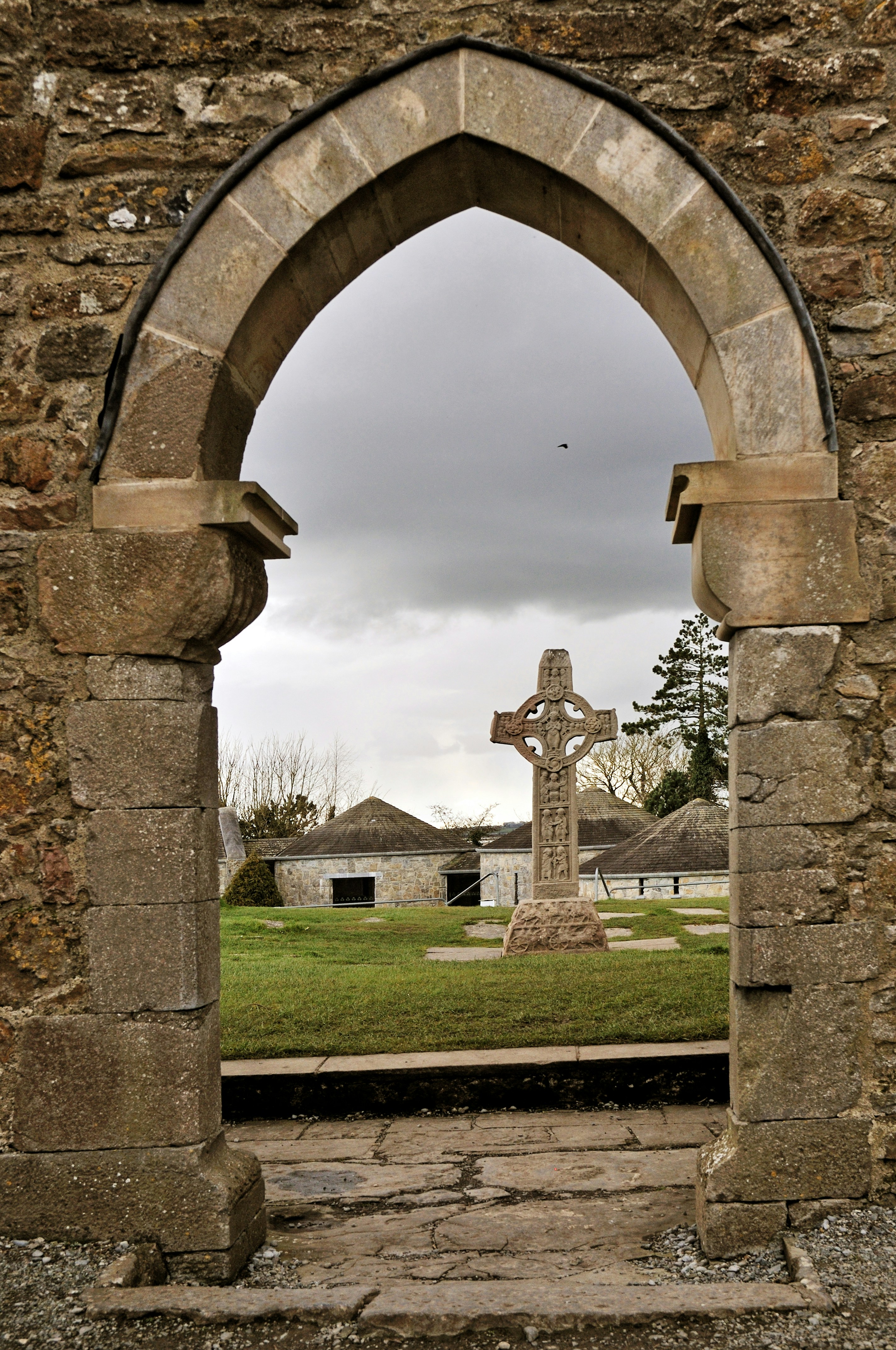 Steinbogen rahmen das keltische Kreuz und Gebäude ein
