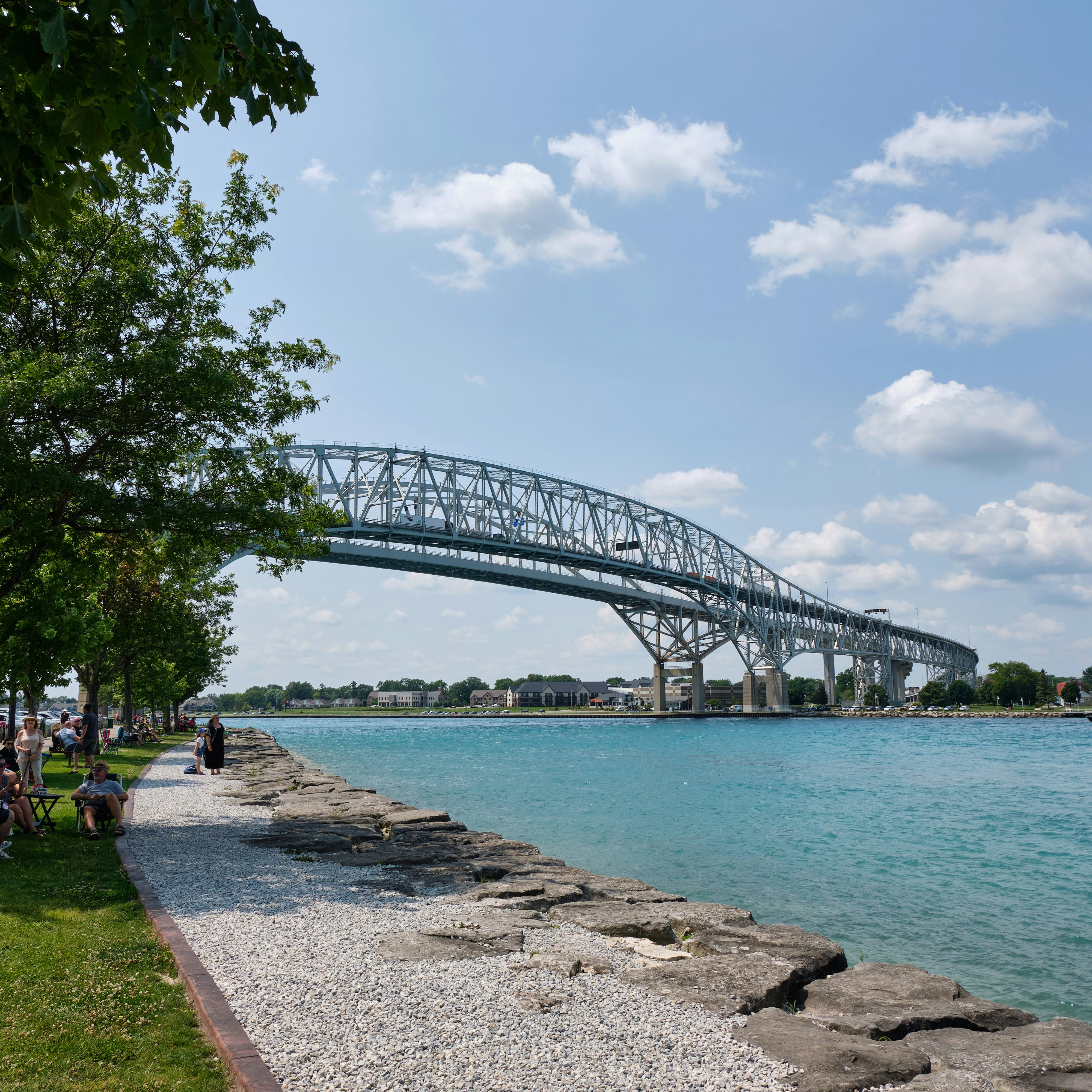 A large metal bridge arches over a bright blue river.