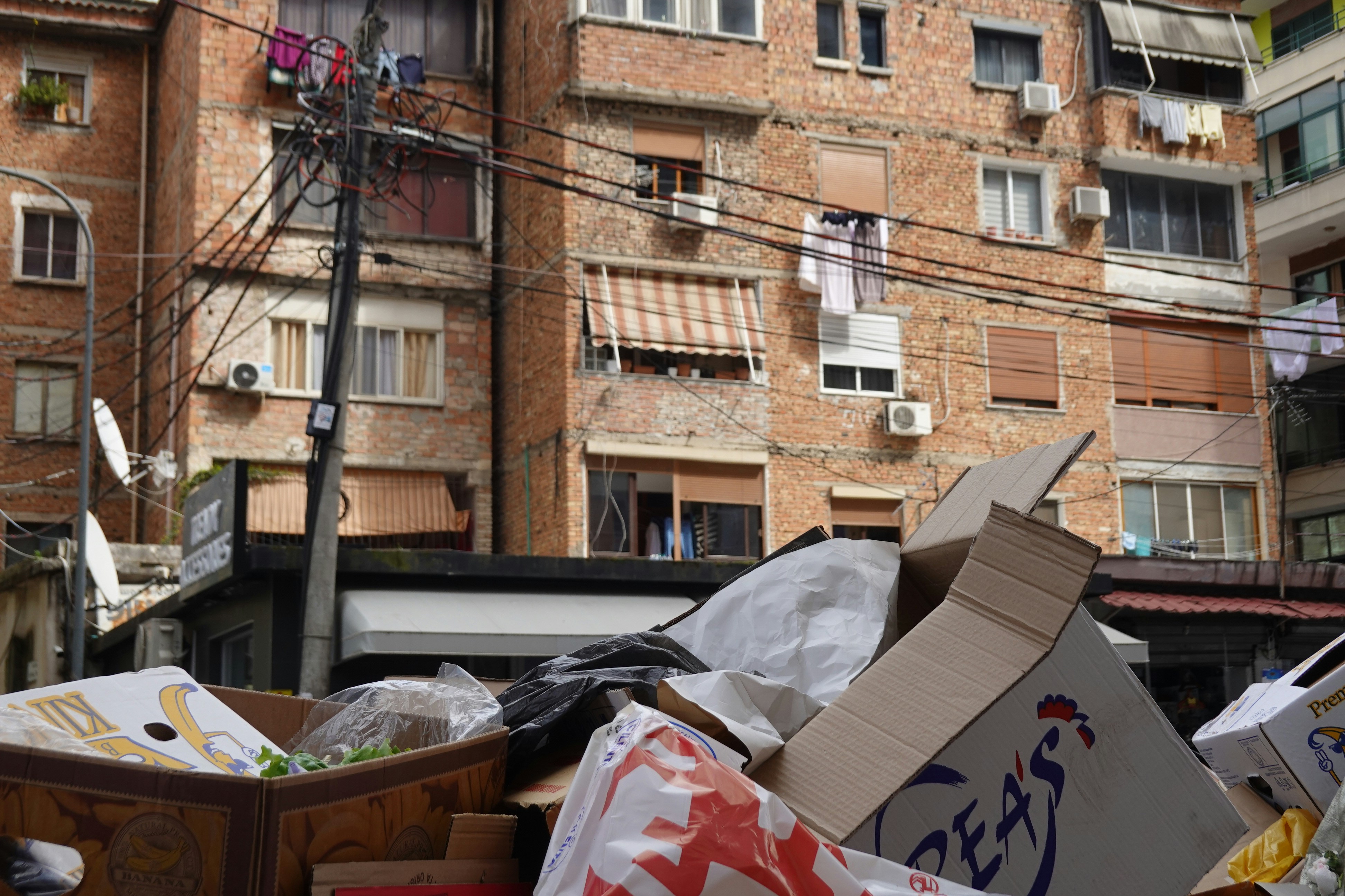 Papeleras desbordadas delante de edificios de ladrillo