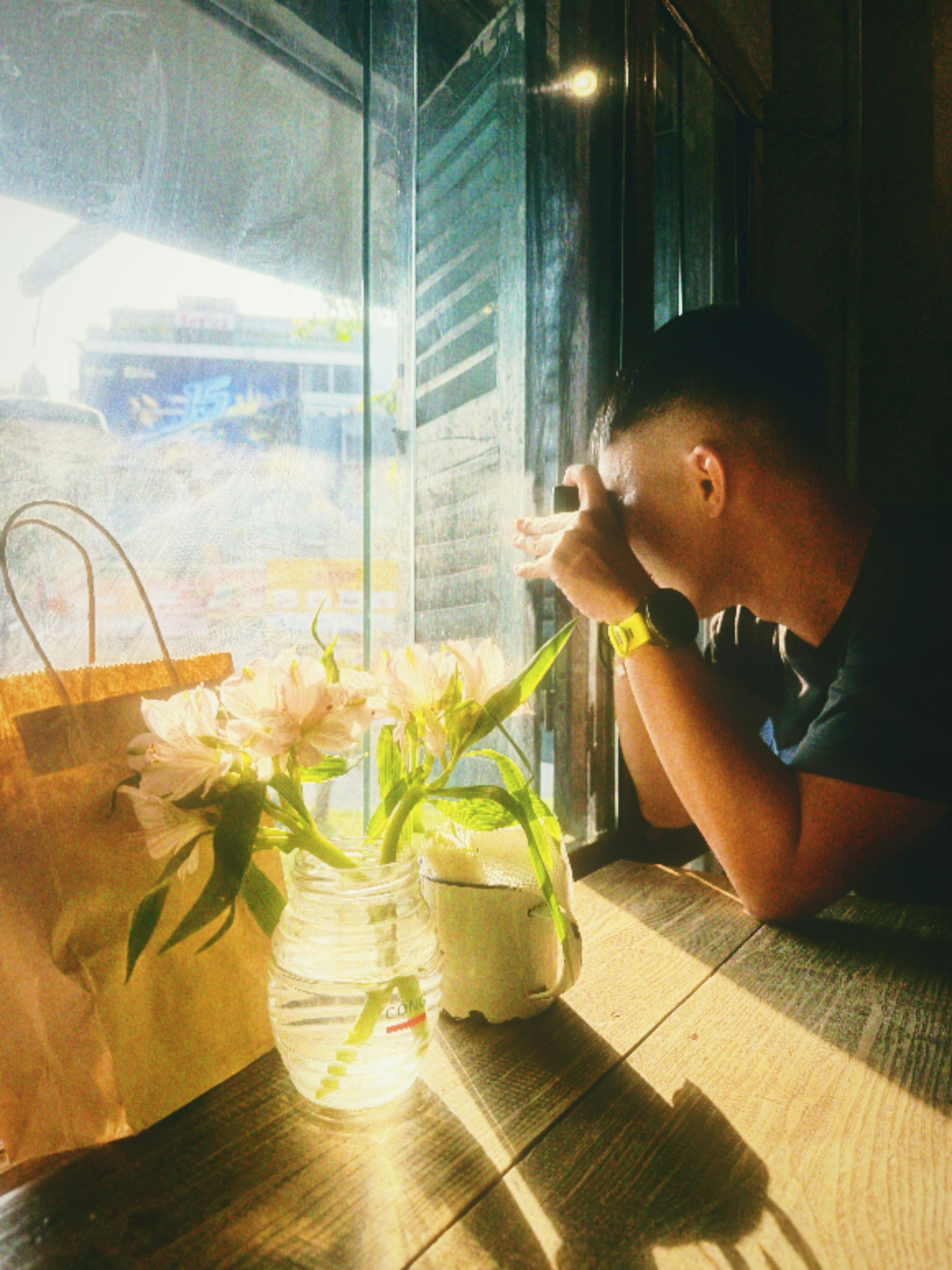Man looking out a cafe window with flowers