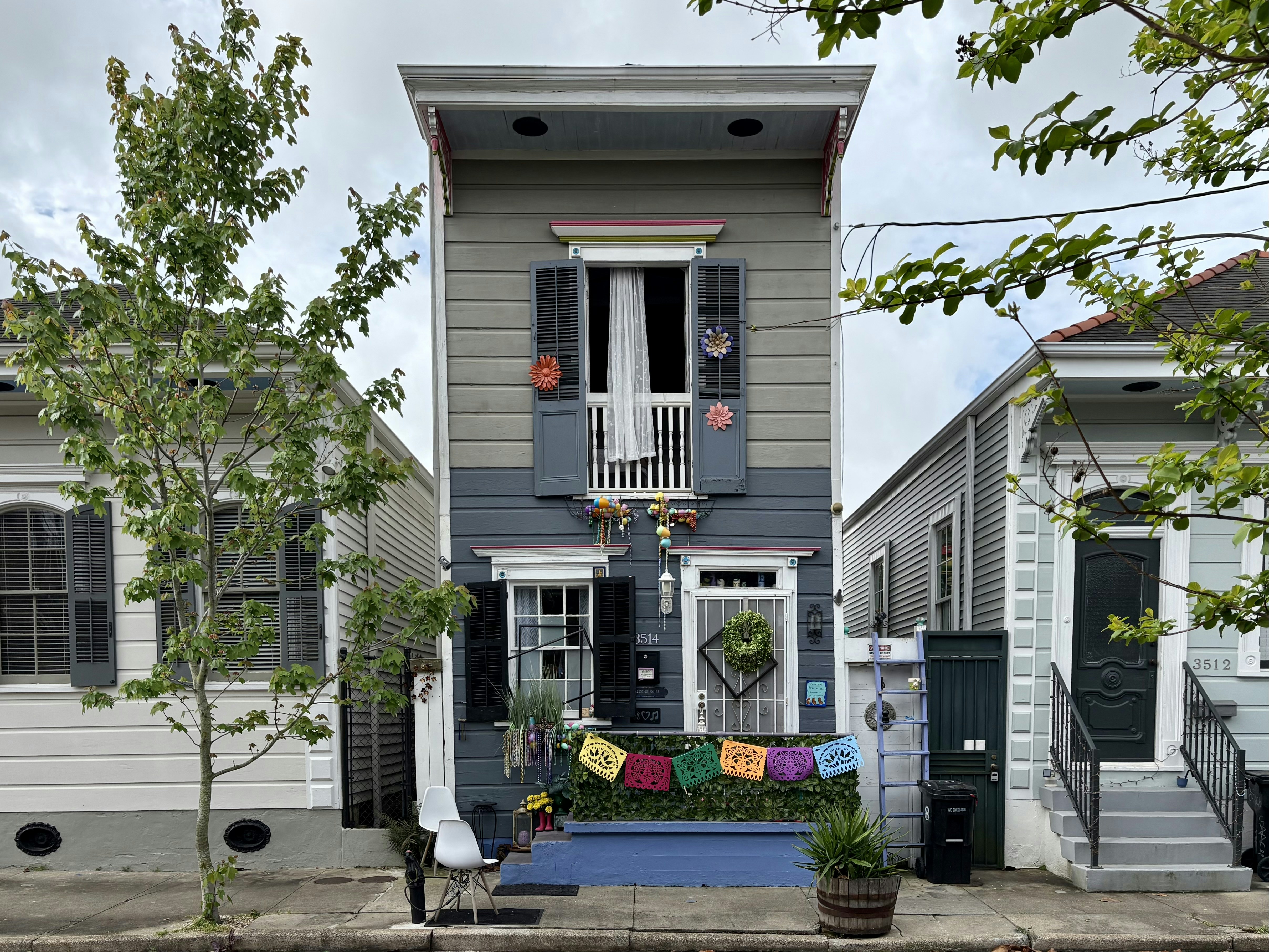 A narrow, colorful house with a balcony and flags.