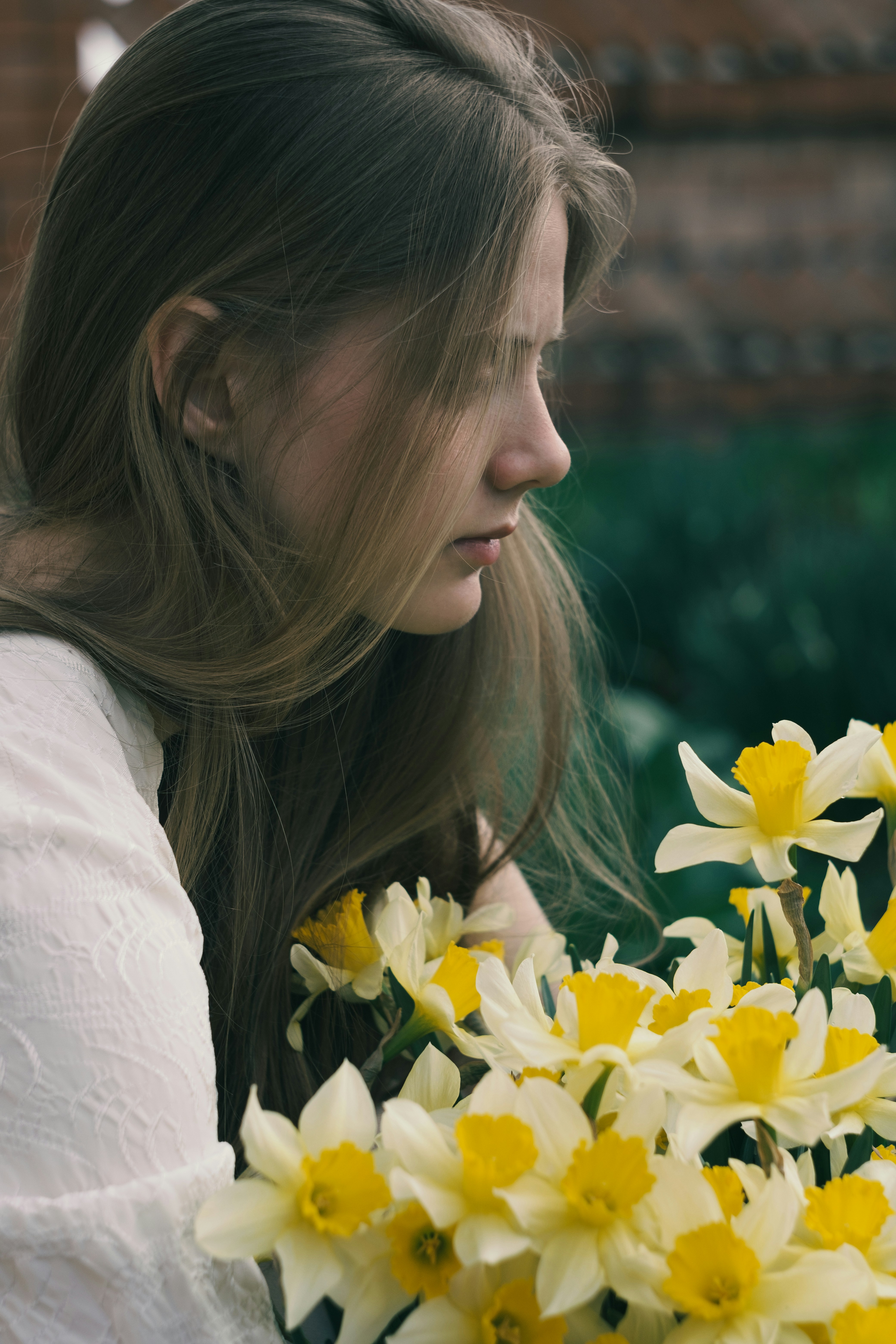 Young woman with long hair near yellow daffodils