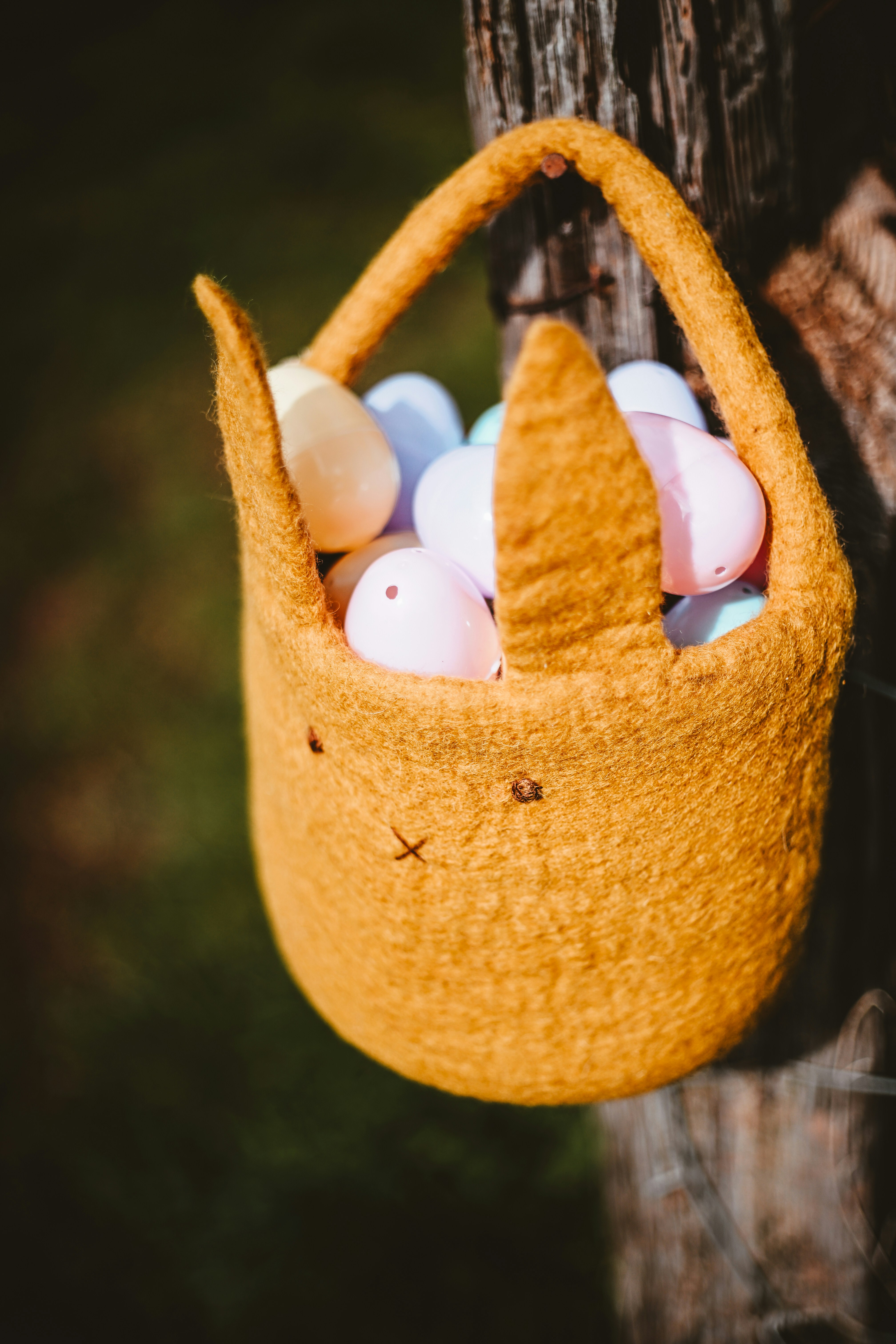 Keranjang Paskah diisi dengan telur pastel yang tergantung di pagar