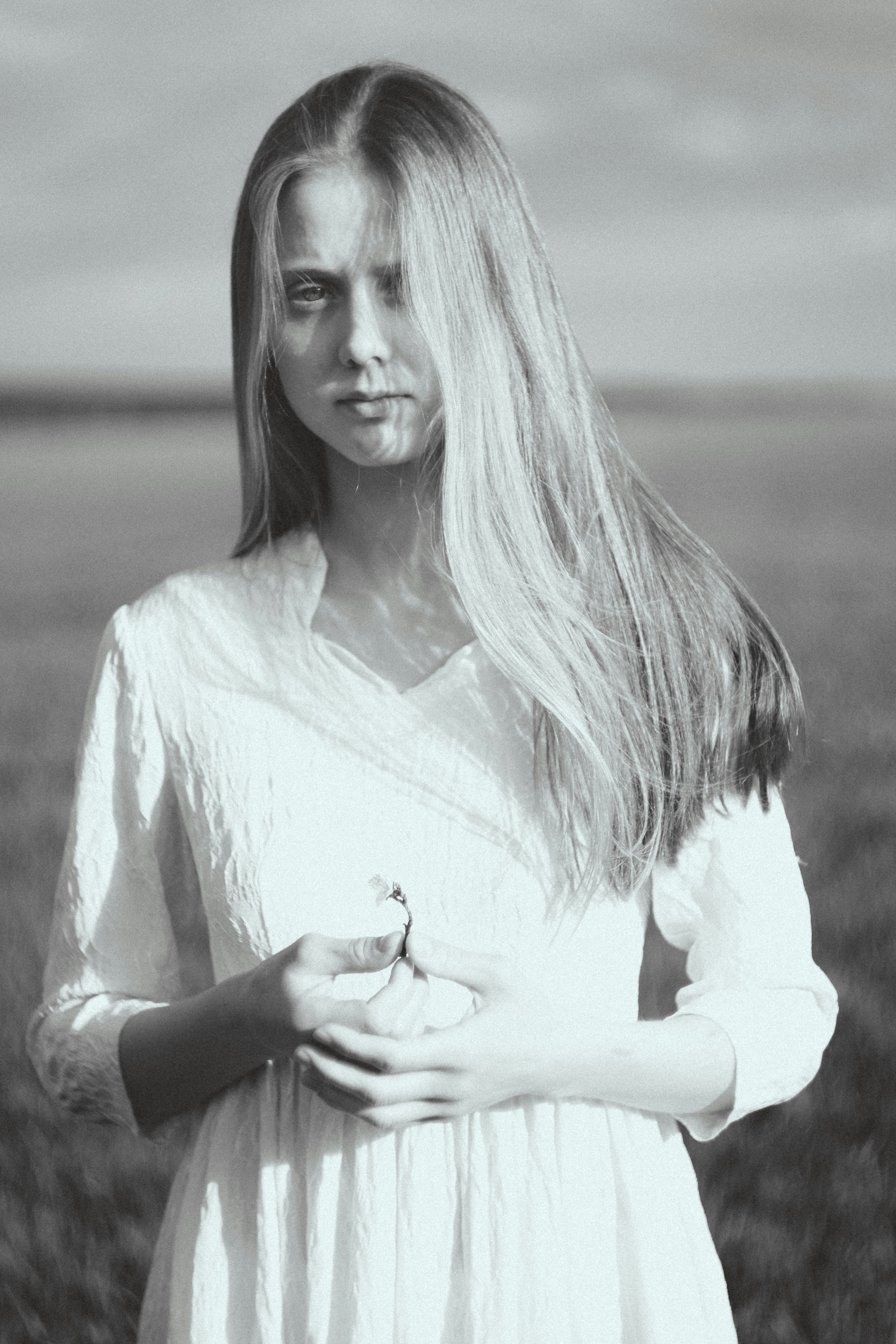 Young woman in white dress holding a small flower