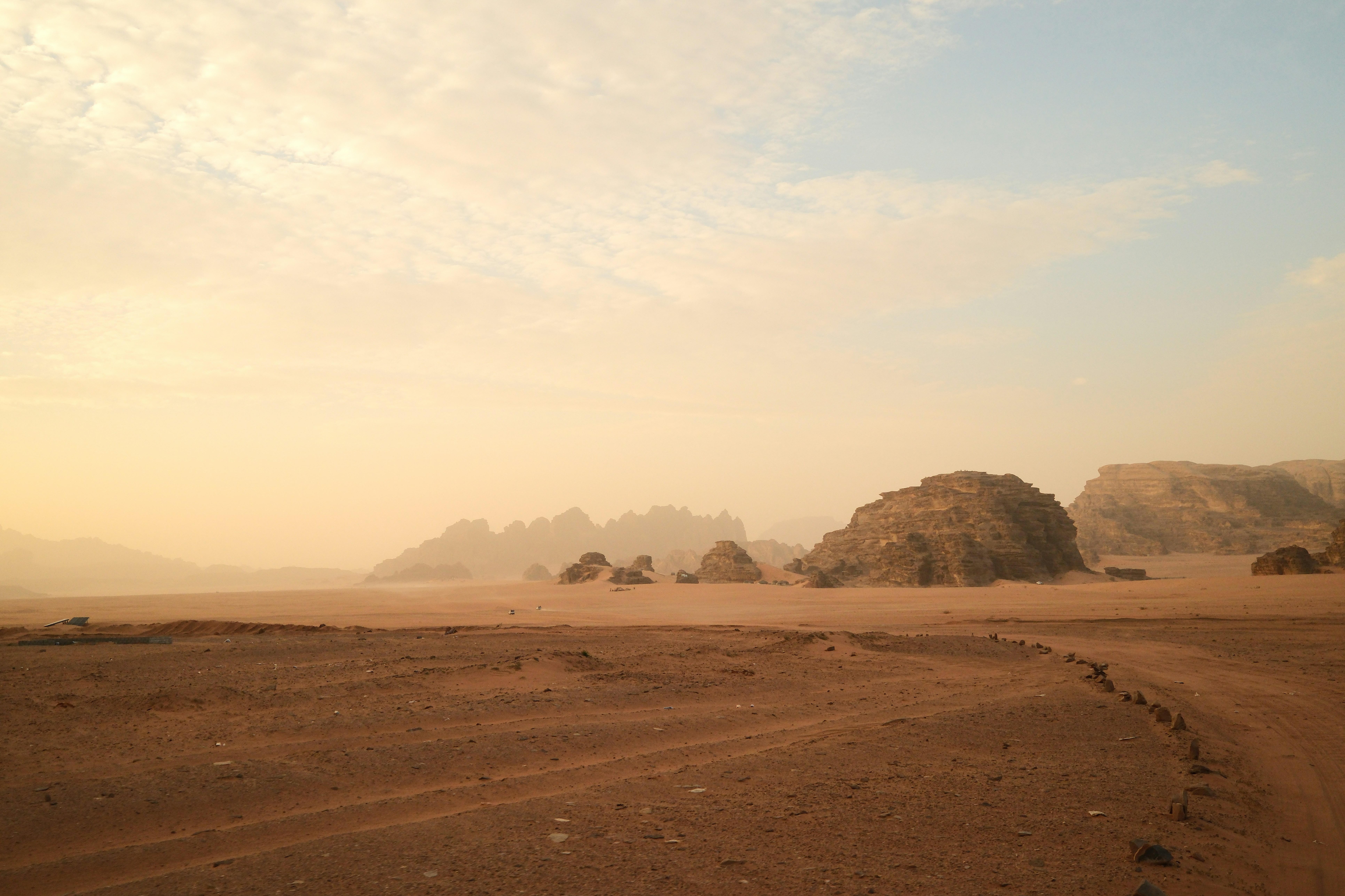 Paysage désertique sablonneux avec formations rocheuses au lever du soleil.