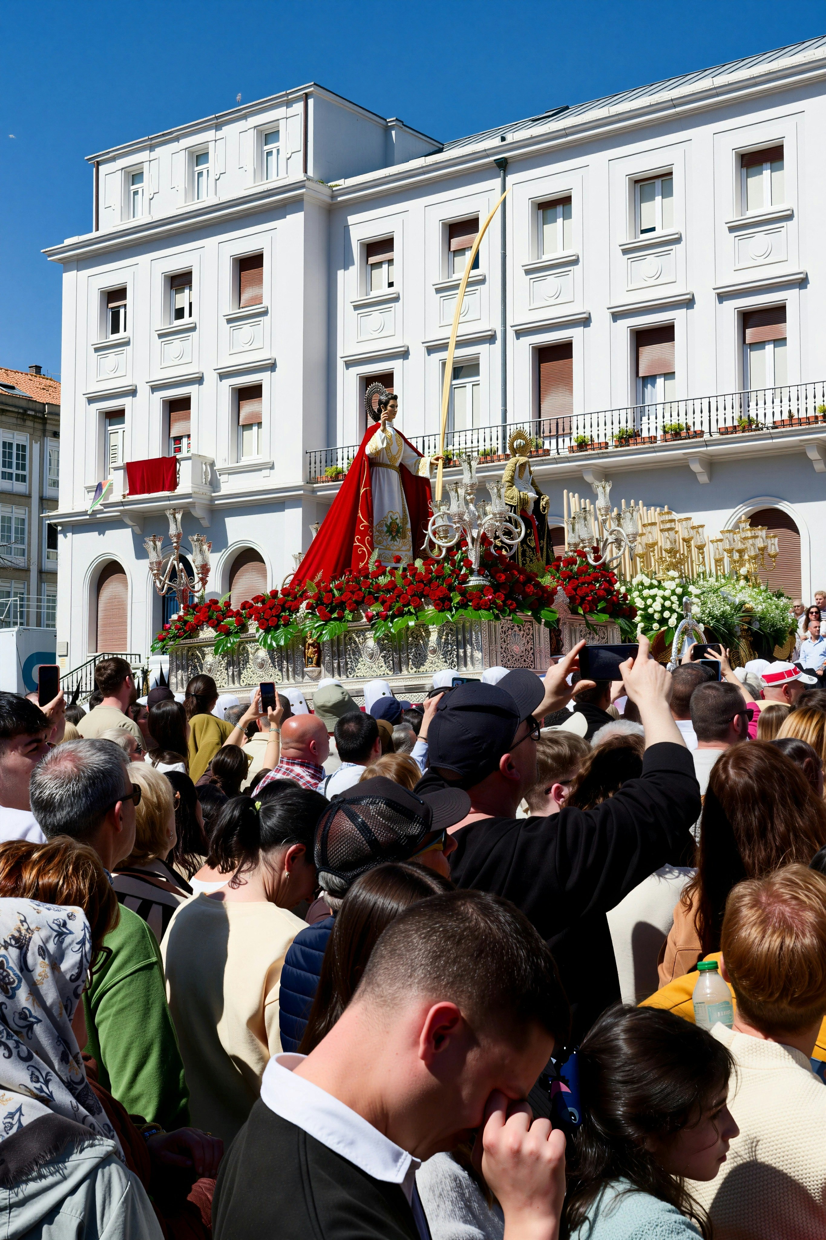 Processione religiosa con carri allegorici e osservazione della folla
