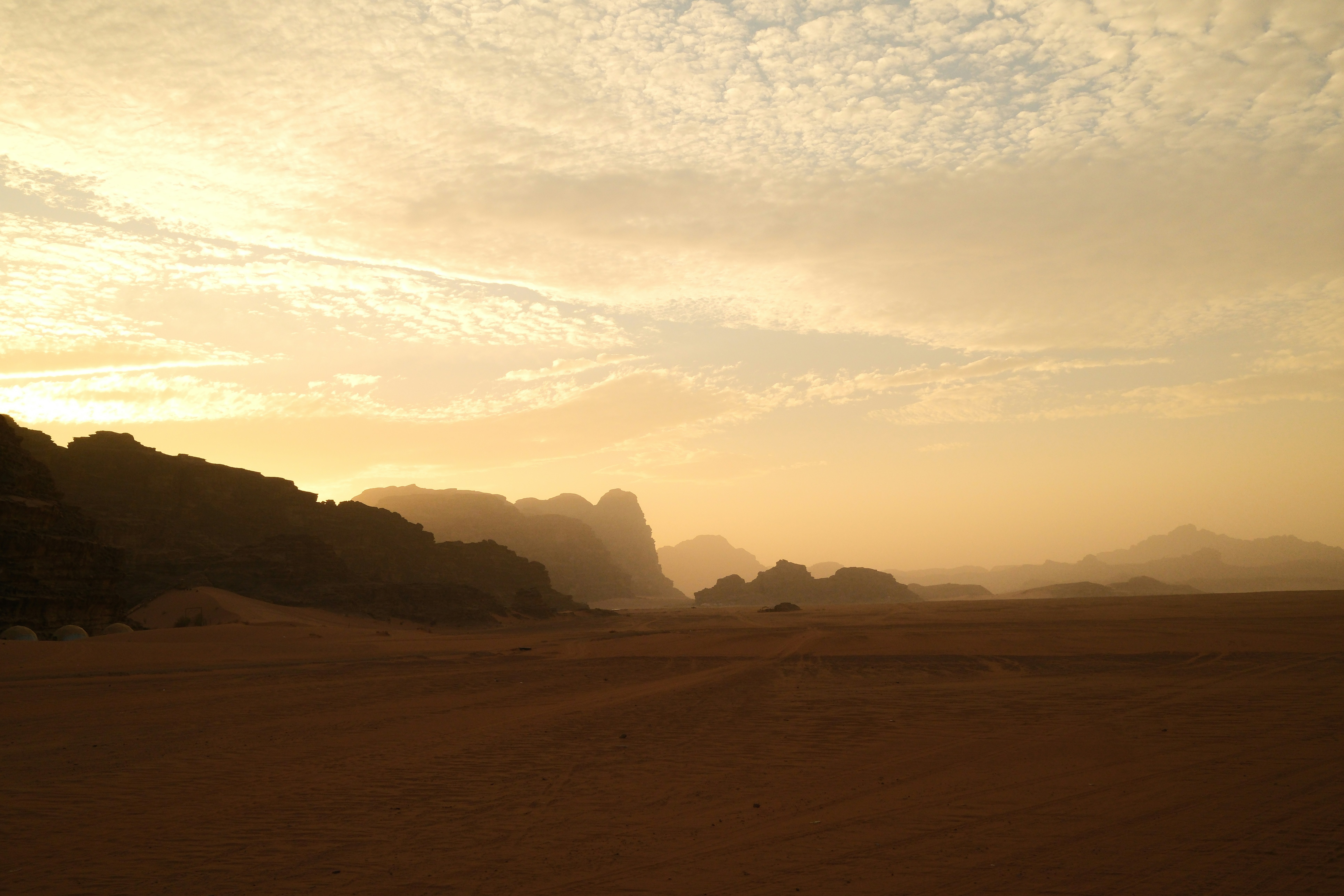 Paysage désertique au coucher du soleil avec des dunes de sable et des montagnes.