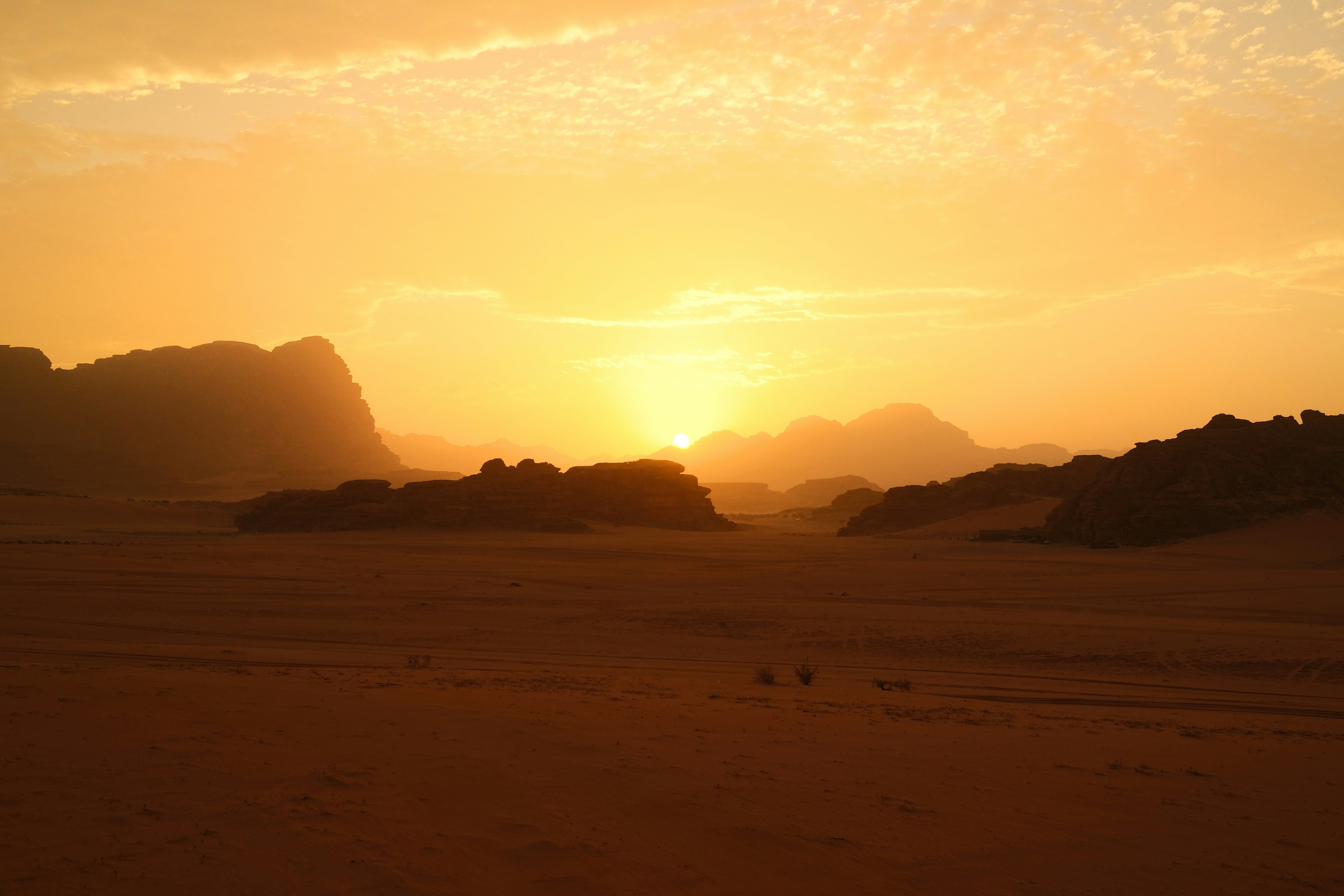 Paysage désertique doré au coucher du soleil avec des montagnes.