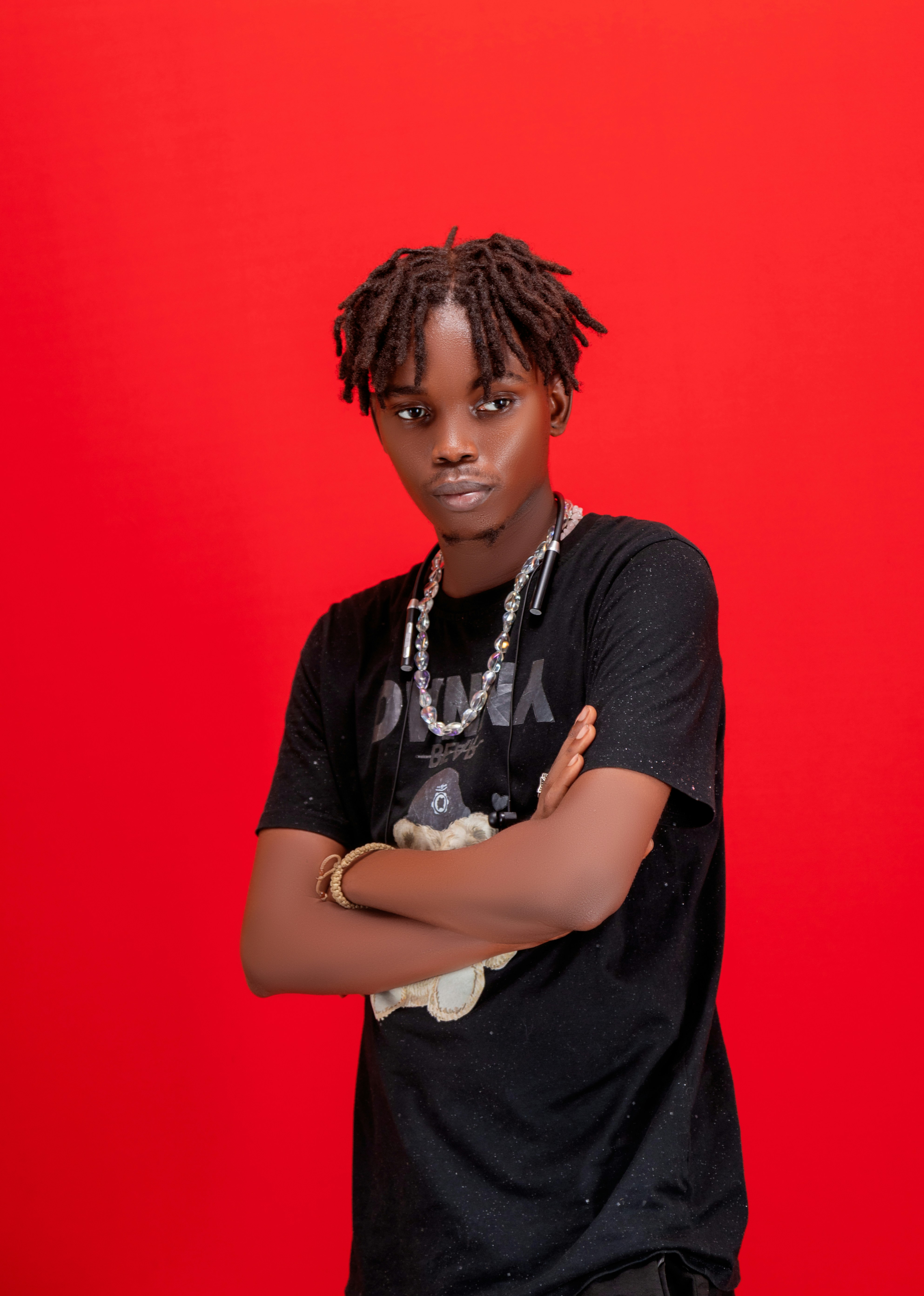Young man with dreadlocks in black shirt and jewelry.