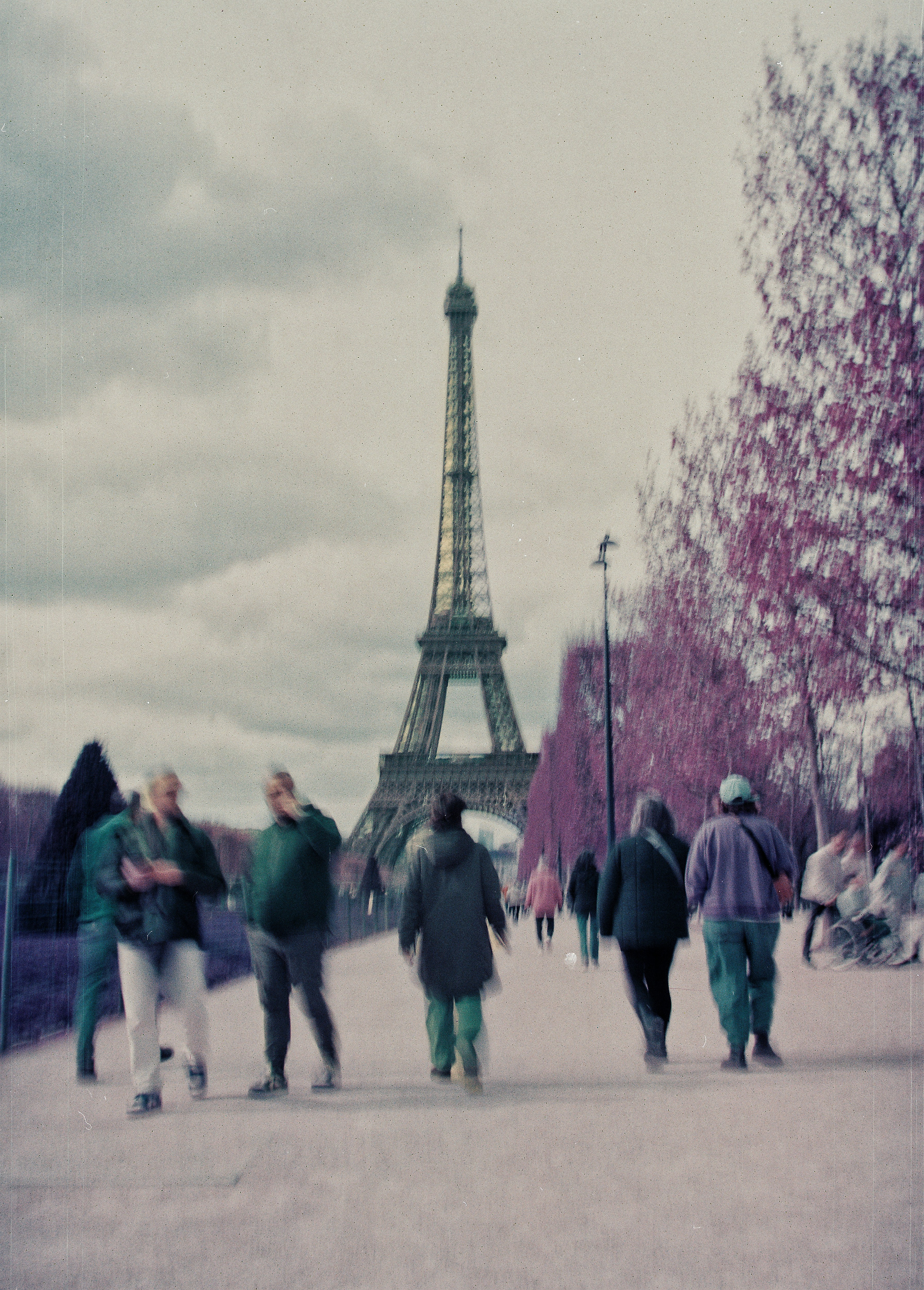 Gente caminando hacia la Torre Eiffel en un día nublado.