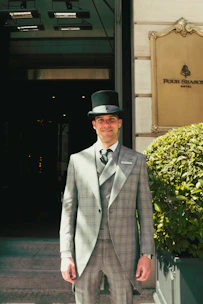 Man in formal attire standing outside four seasons hotel.