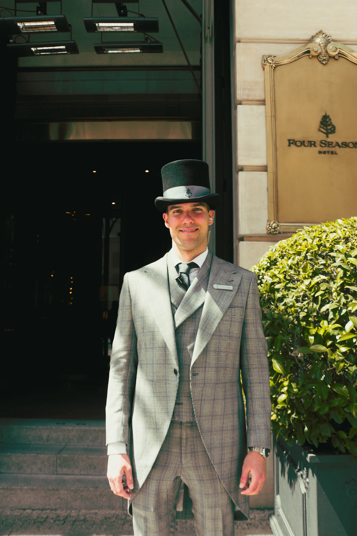 정장을 갖춰 입은 호텔 직원이 호텔 앞에 서 있는 모습, 화이트 라벨 라이선스의 외부 브랜드 서비스를 상징