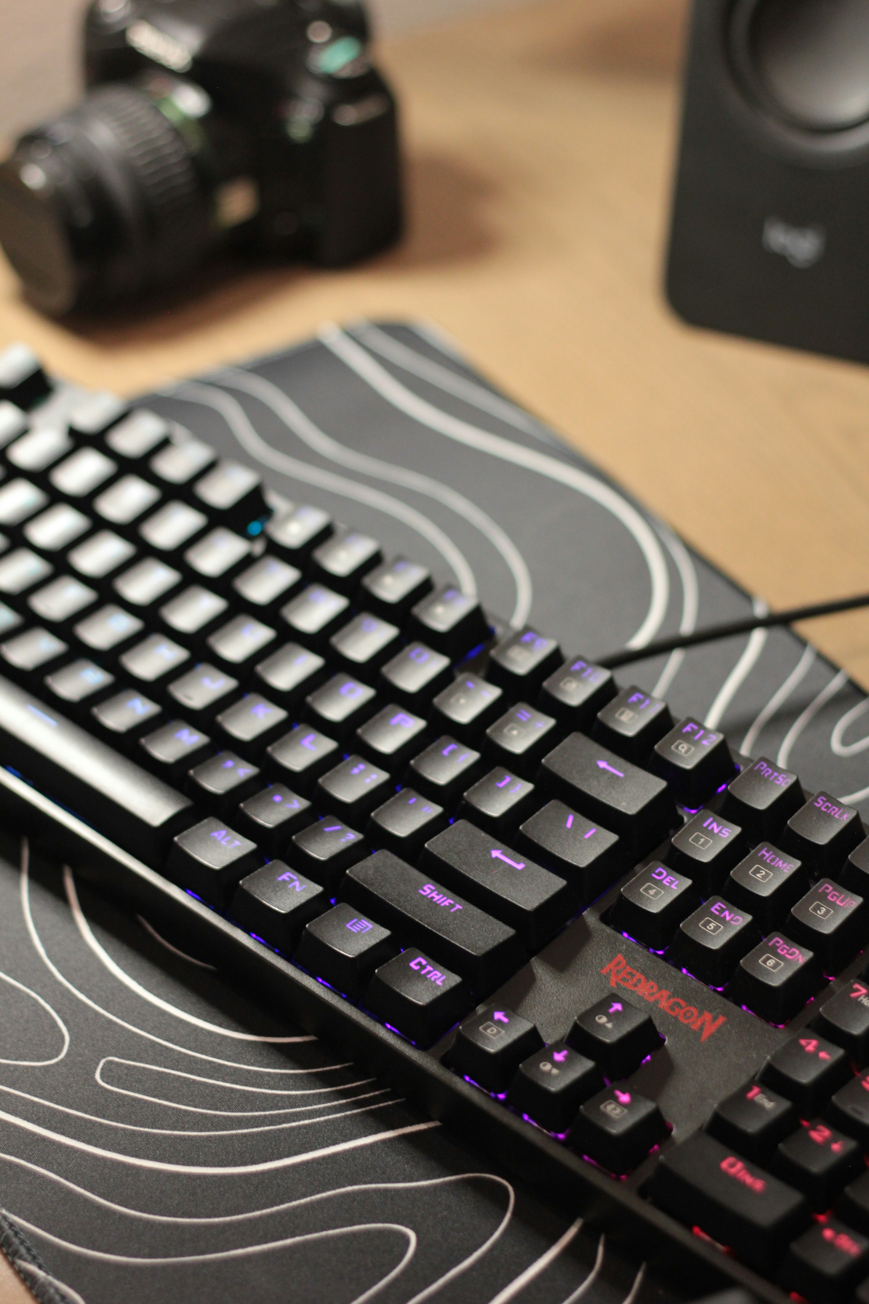 Un teclado mecánico negro con luces RGB sobre un escritorio.