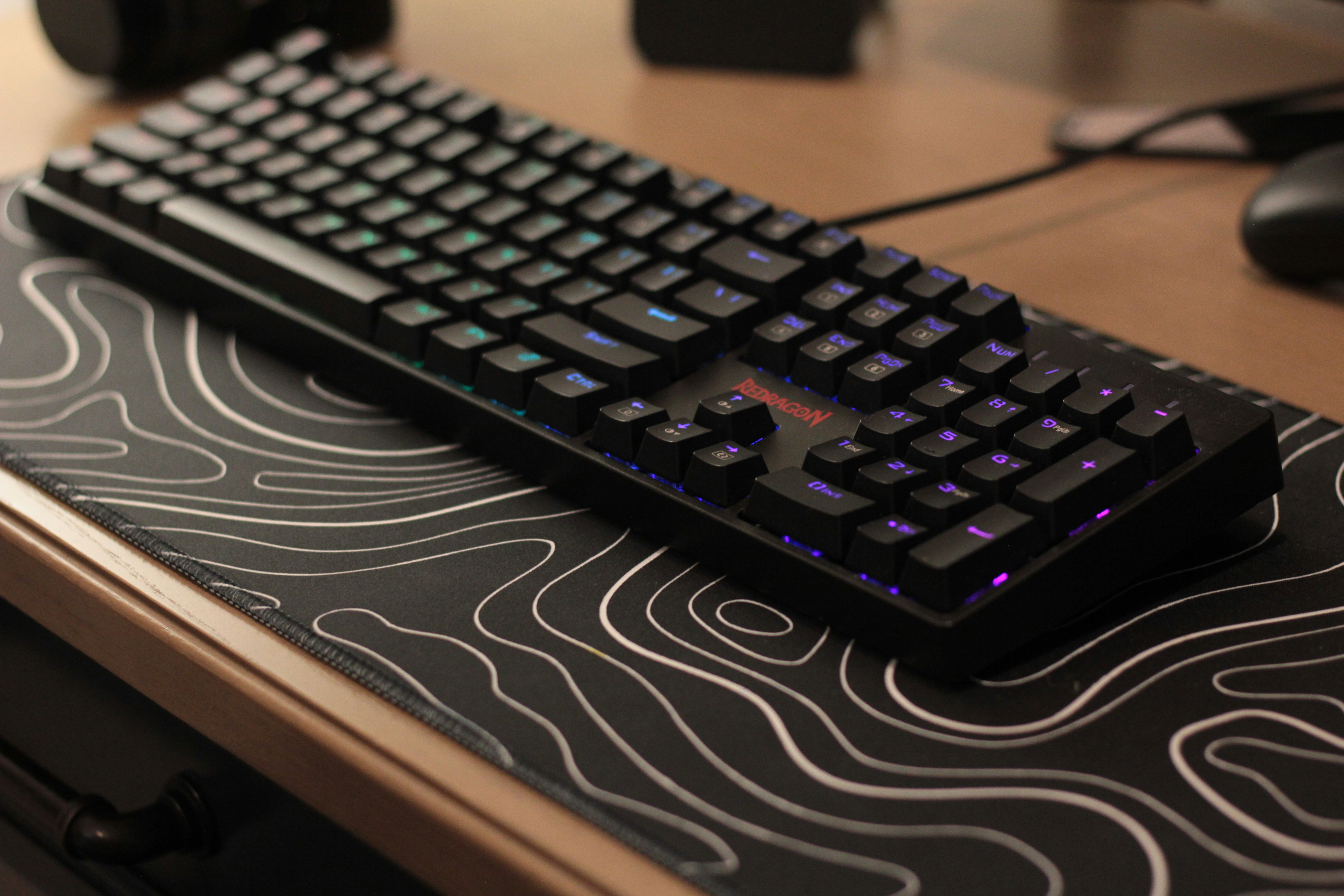 Un teclado mecánico negro con retroiluminación morada.