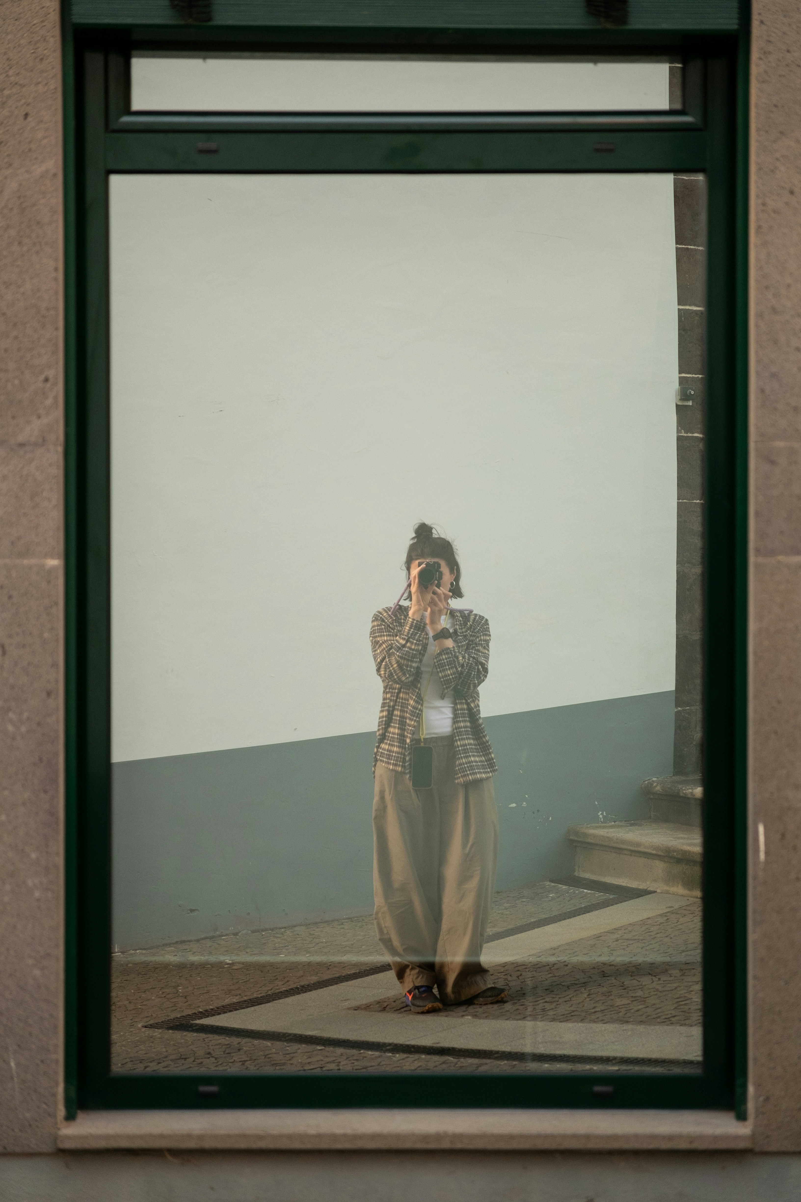 Woman taking a selfie in a large window reflection