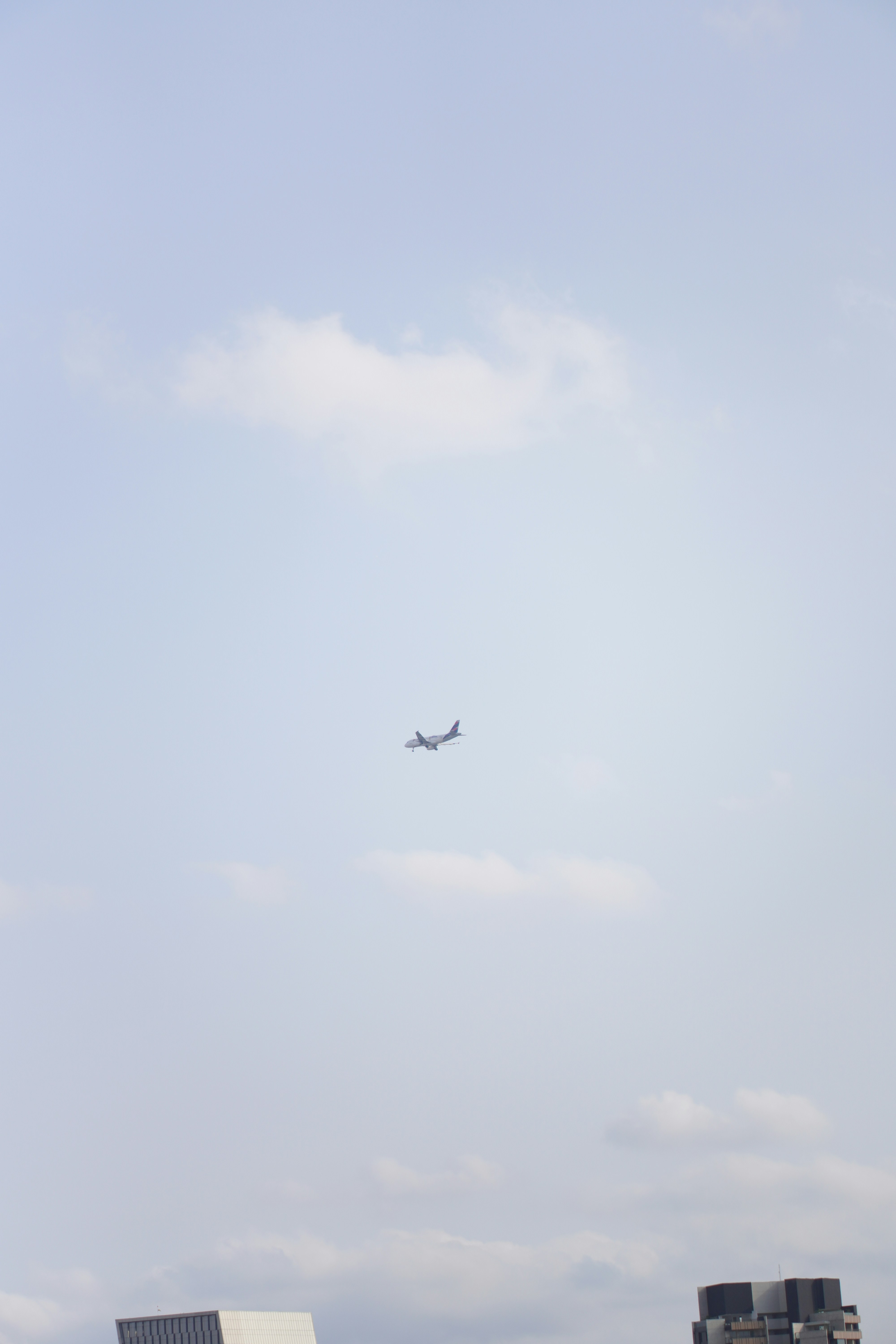 Airplane flying in a cloudy sky above buildings