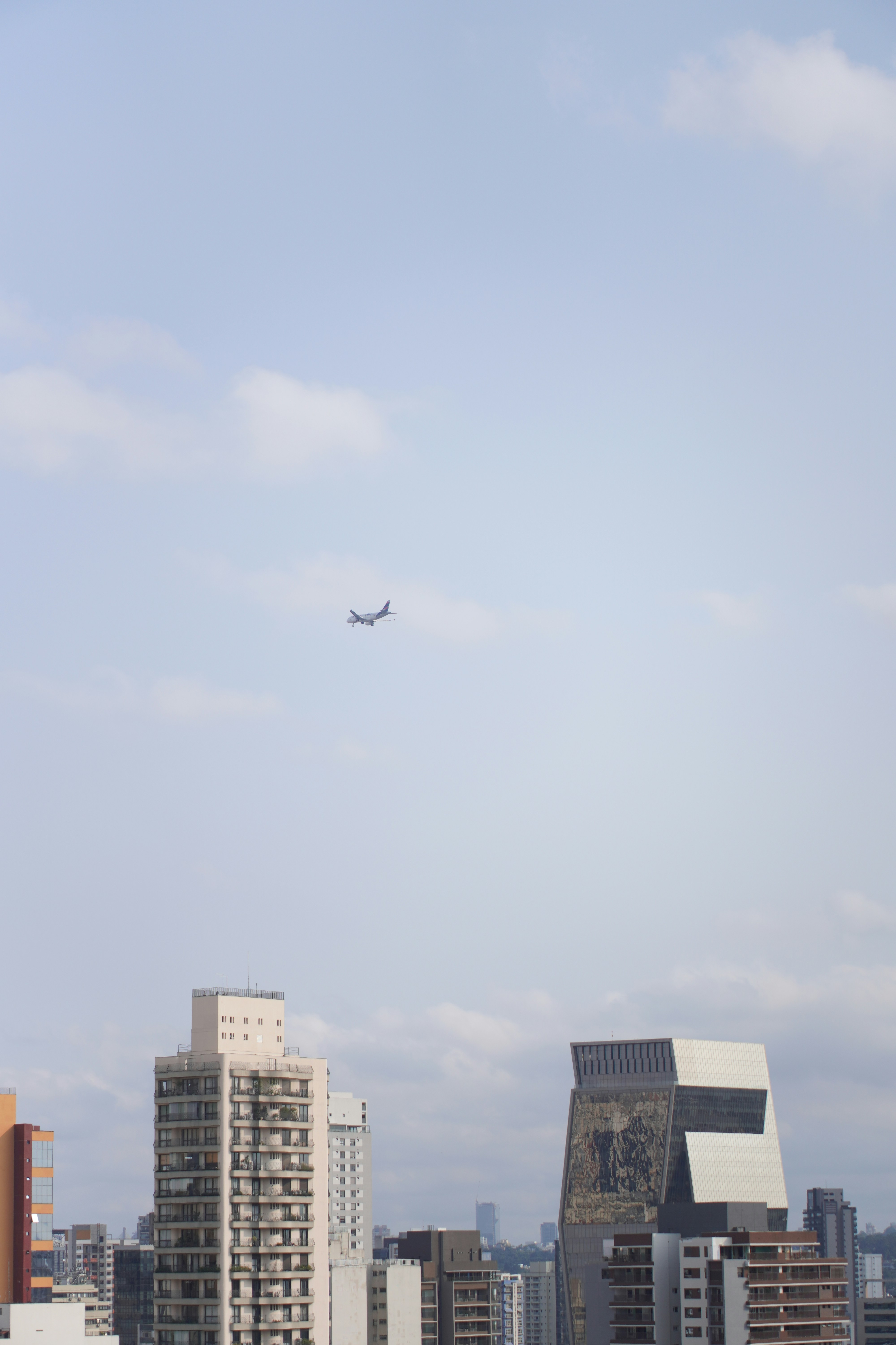 Airplane flying over buildings under a cloudy sky