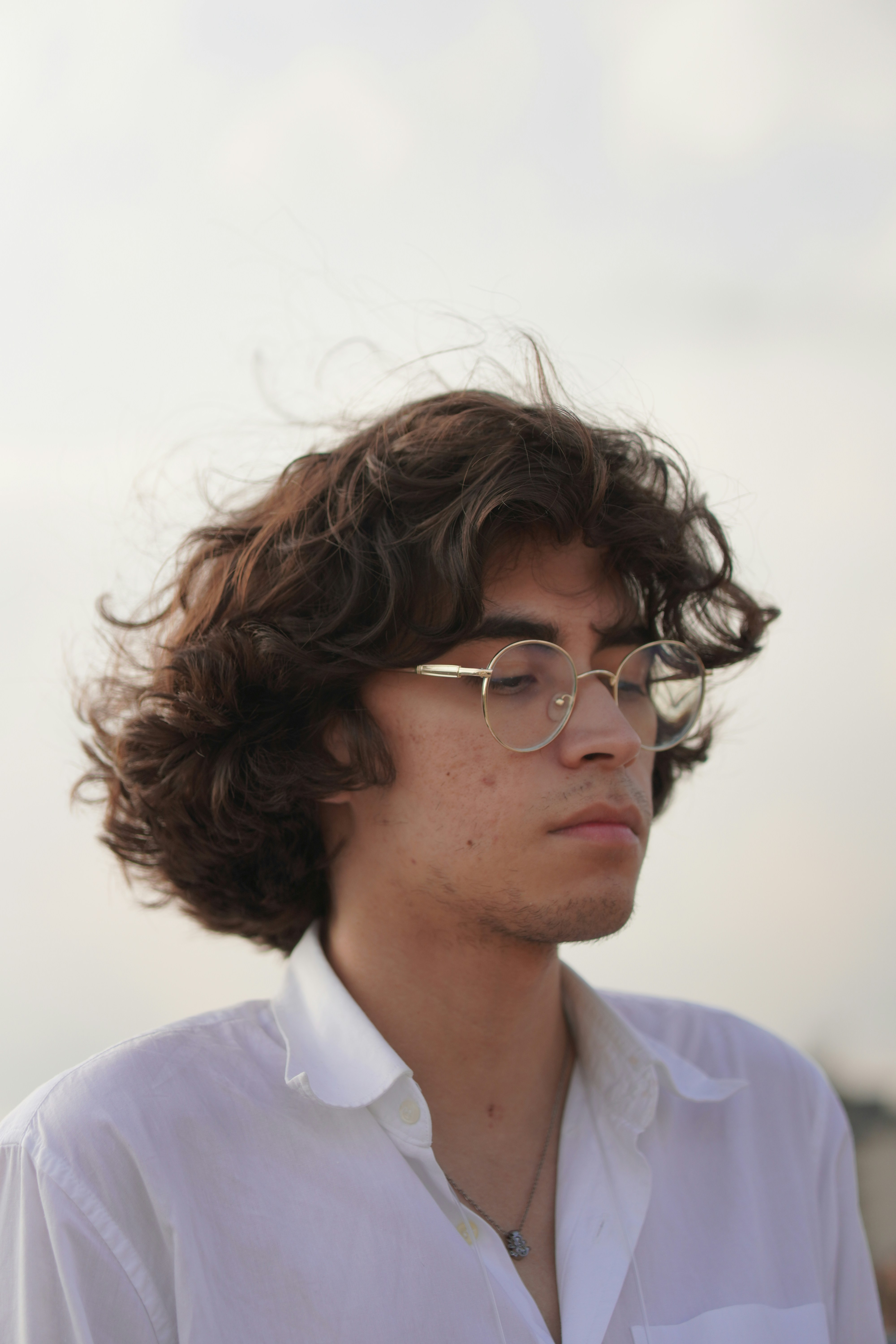 Young man with curly hair and glasses outdoors