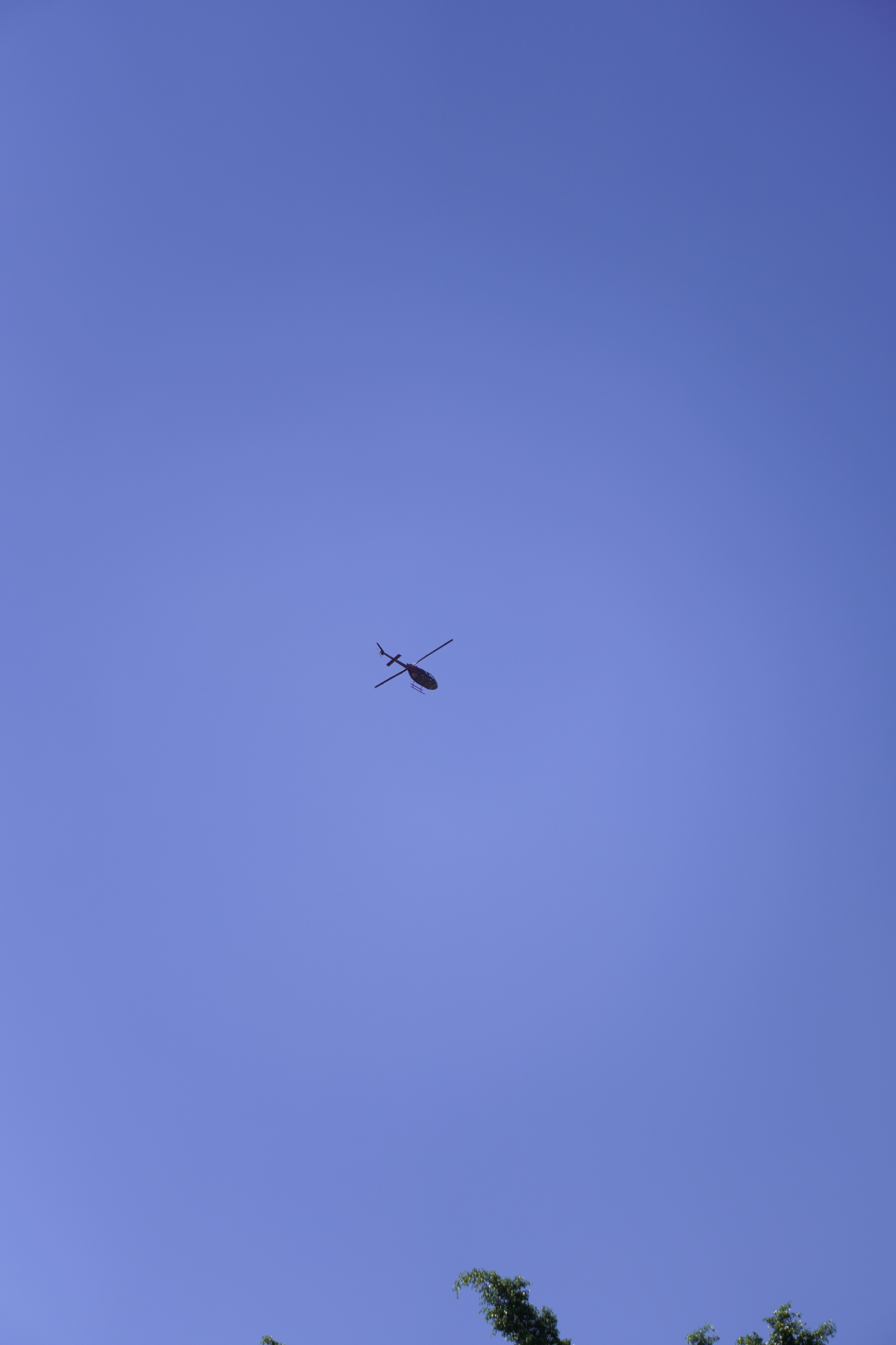 A helicopter flying in the clear blue sky.