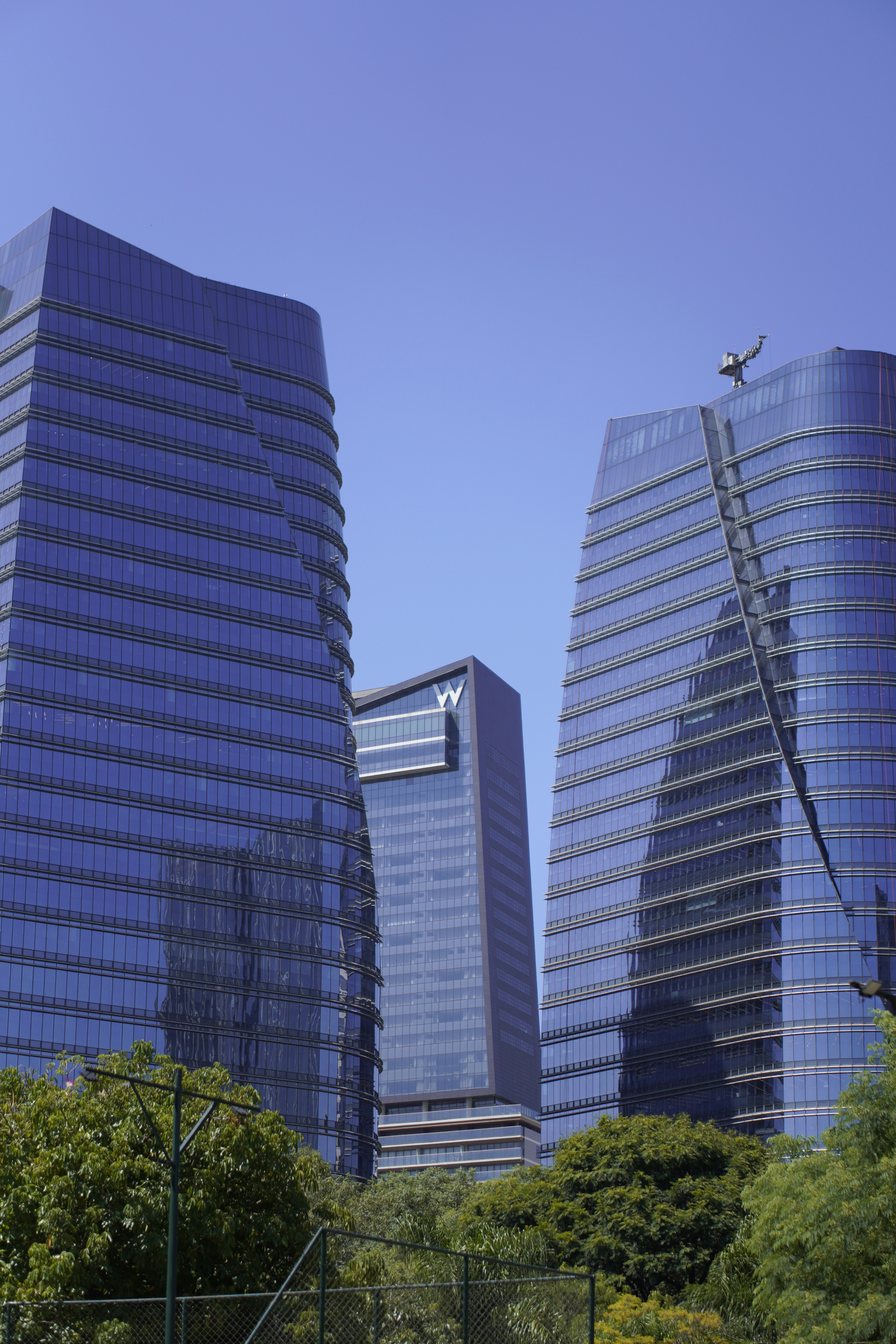 Modern glass skyscrapers rise against a clear blue sky.