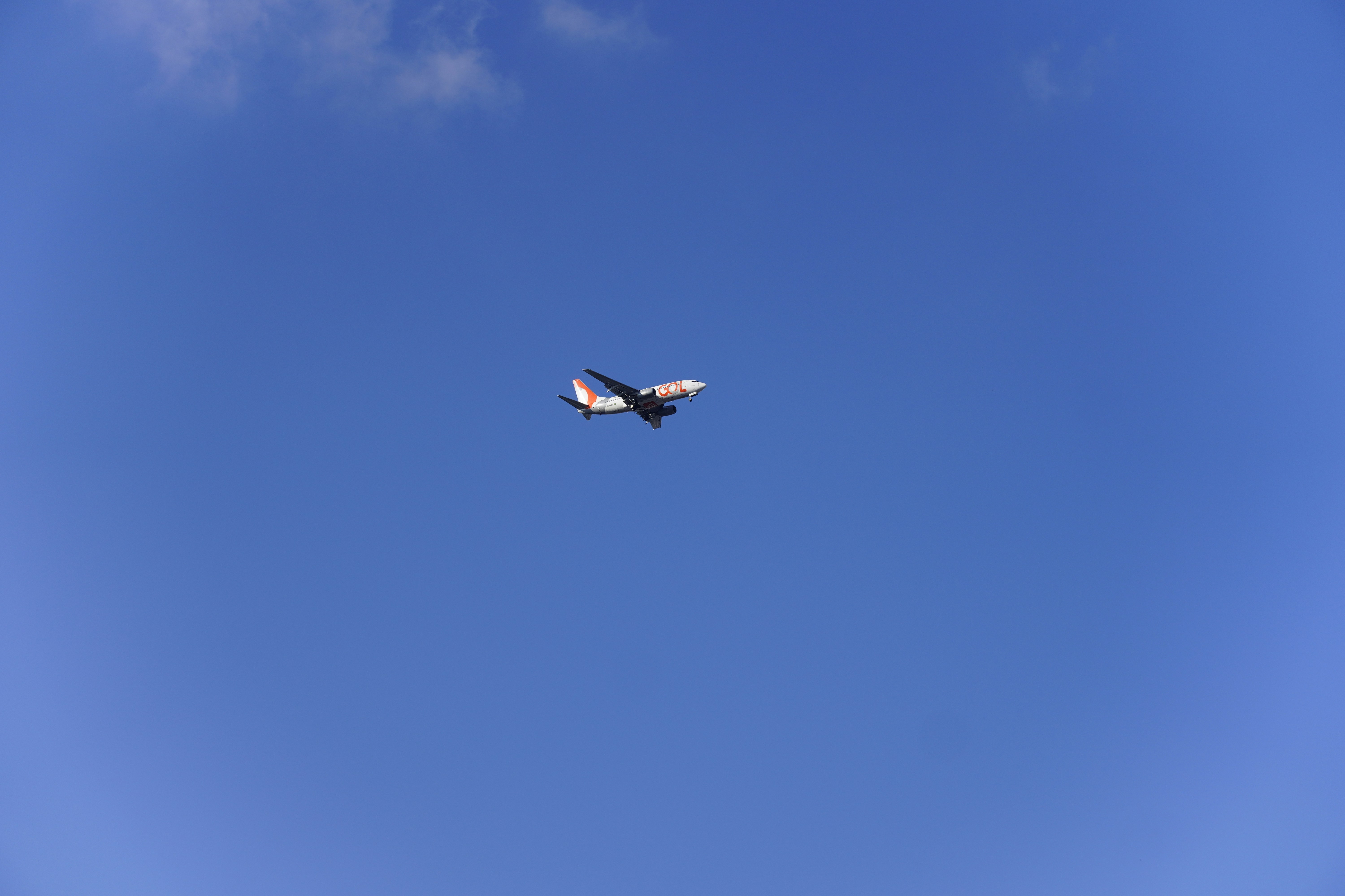 An airplane flies across a clear blue sky.