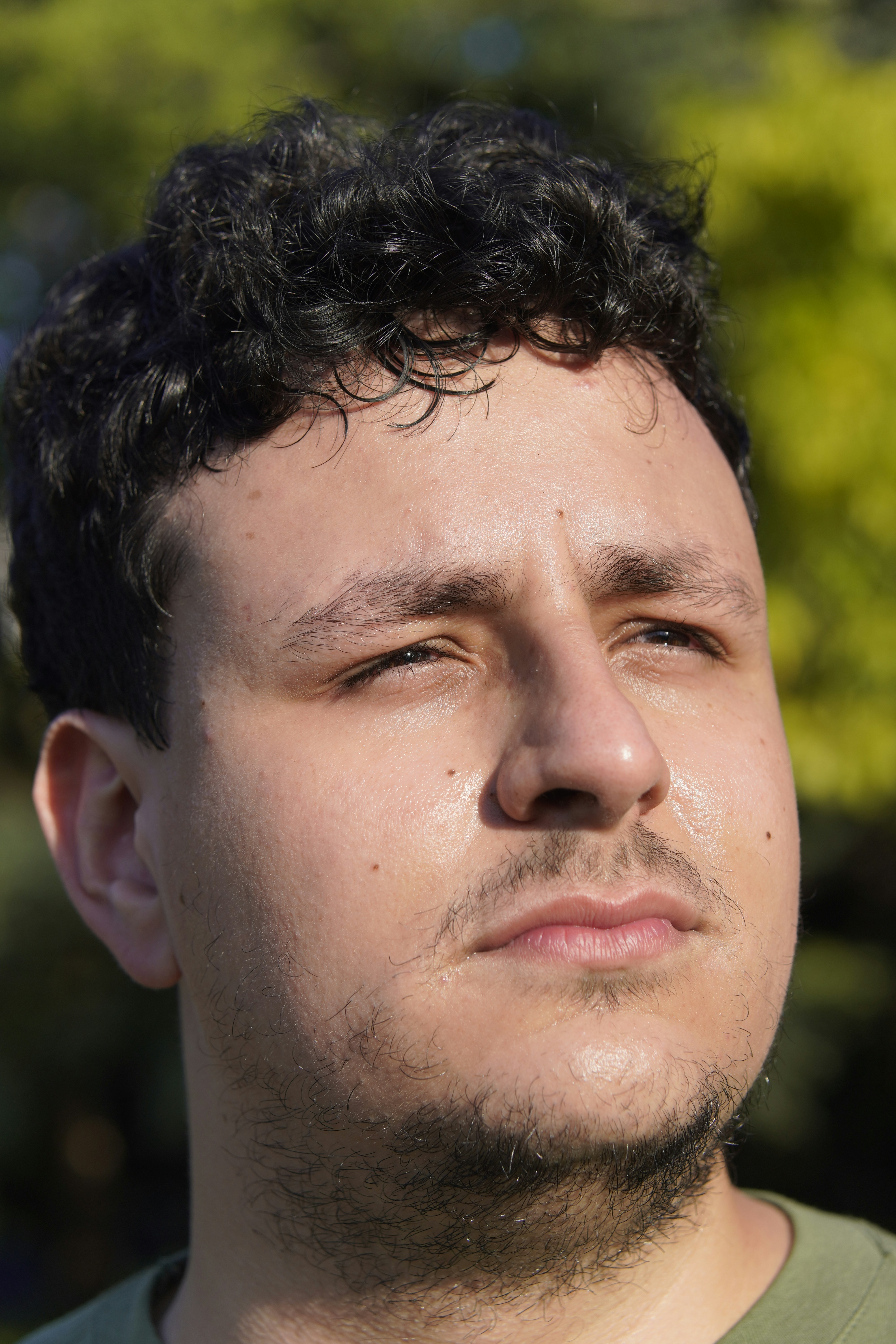 A man with dark curly hair looks up
