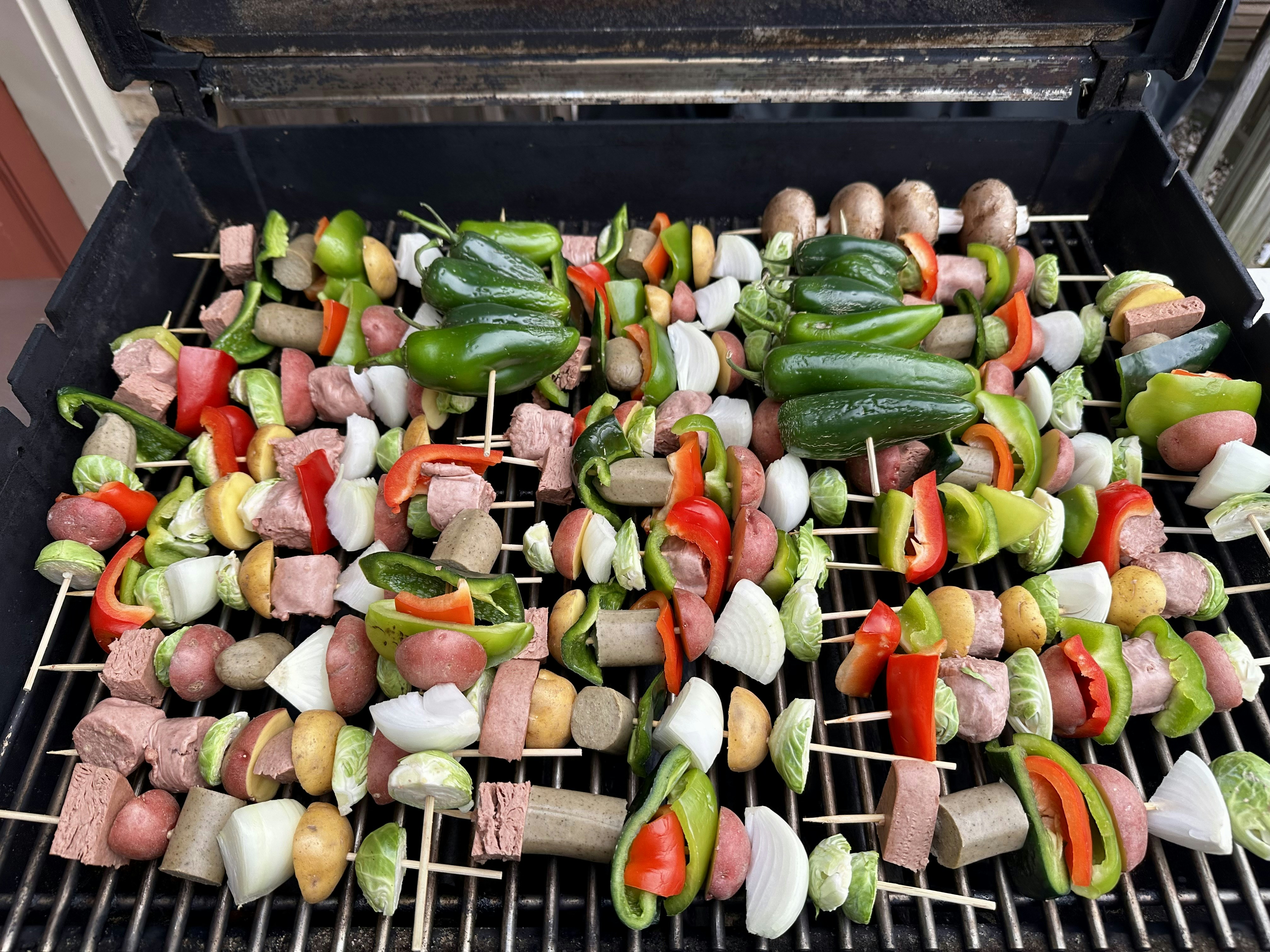 Pinchetas con carne y verduras cocinándose en una parrilla.