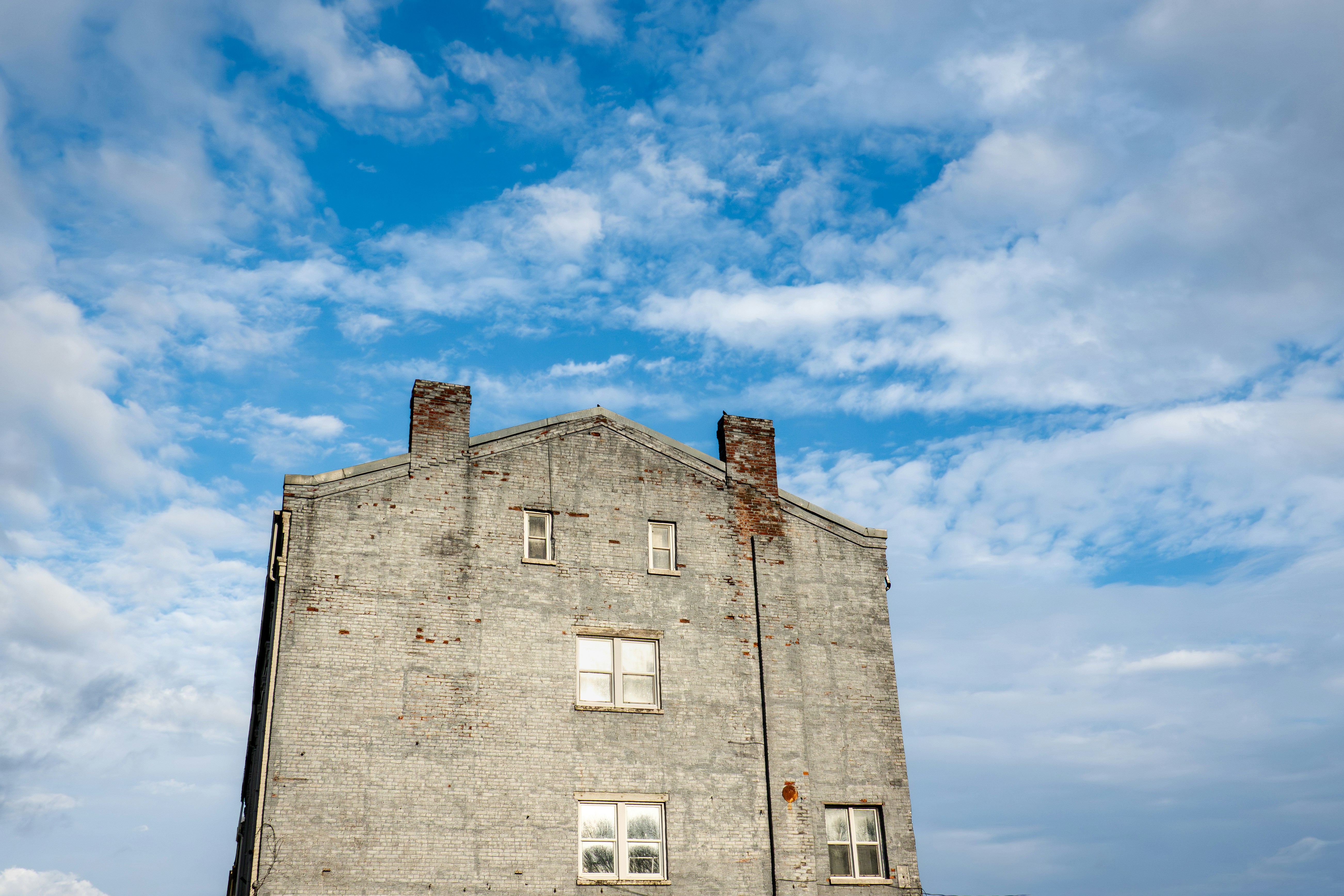 A weathered brick building against a cloudy blue sky