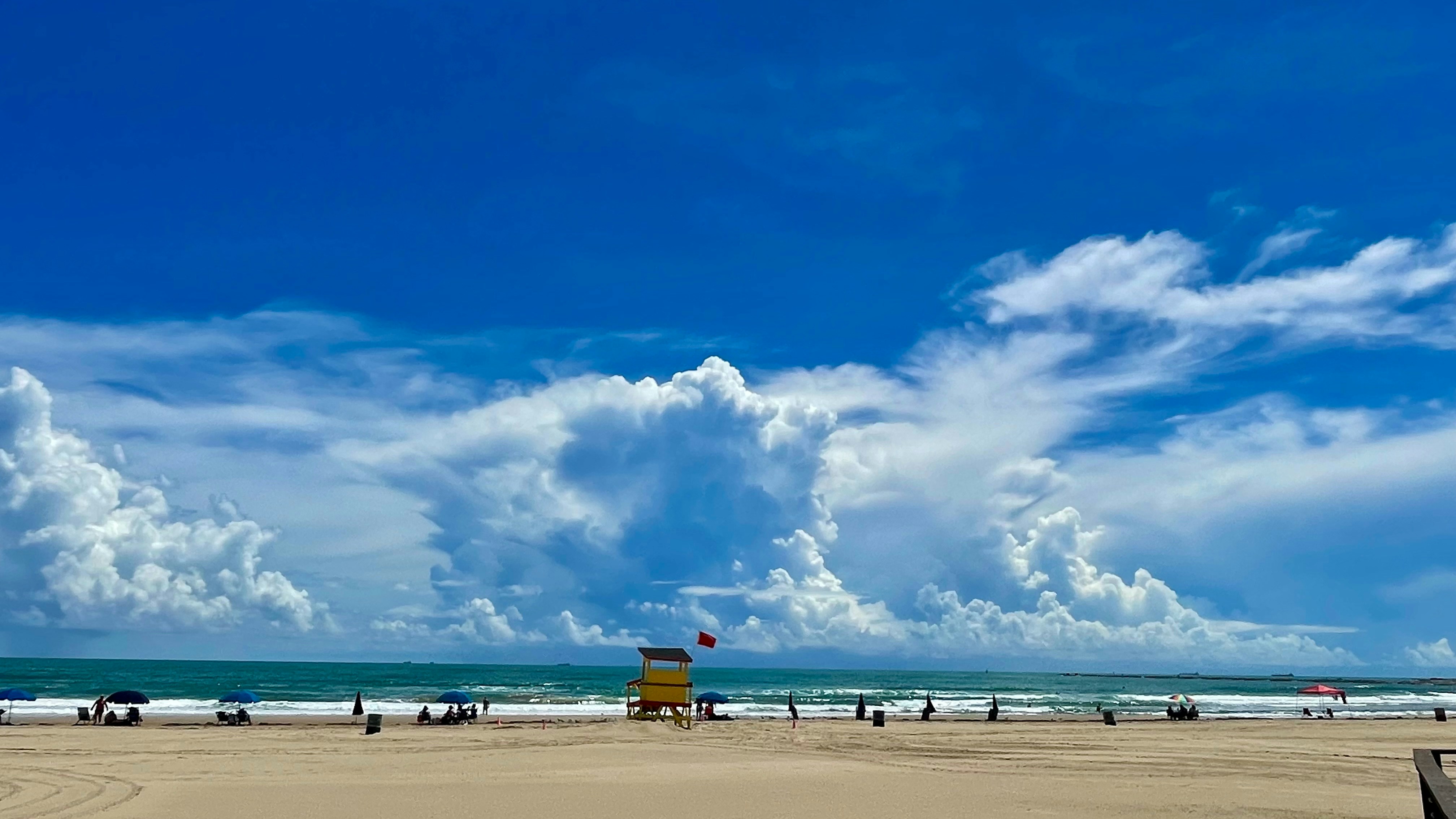 Una spiaggia soleggiata con nuvole sparse e onde oceaniche.