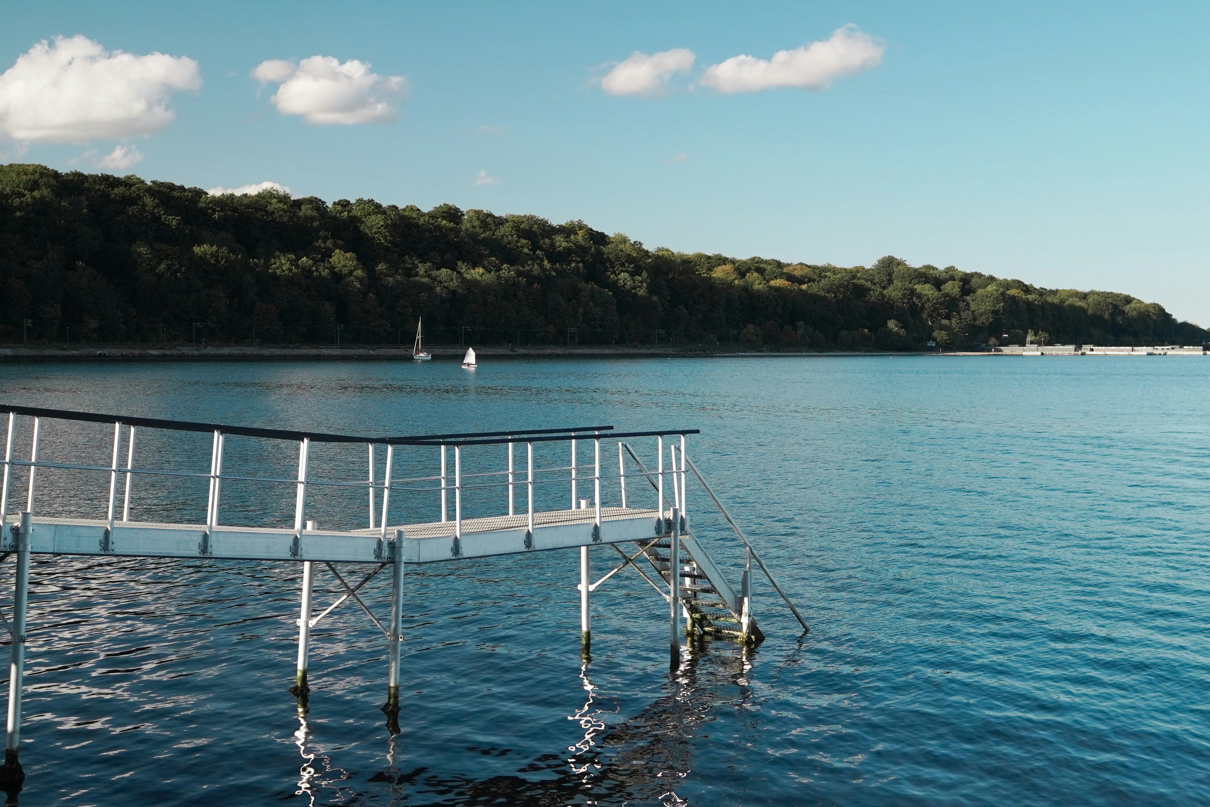 A white pier extends into a calm blue lake