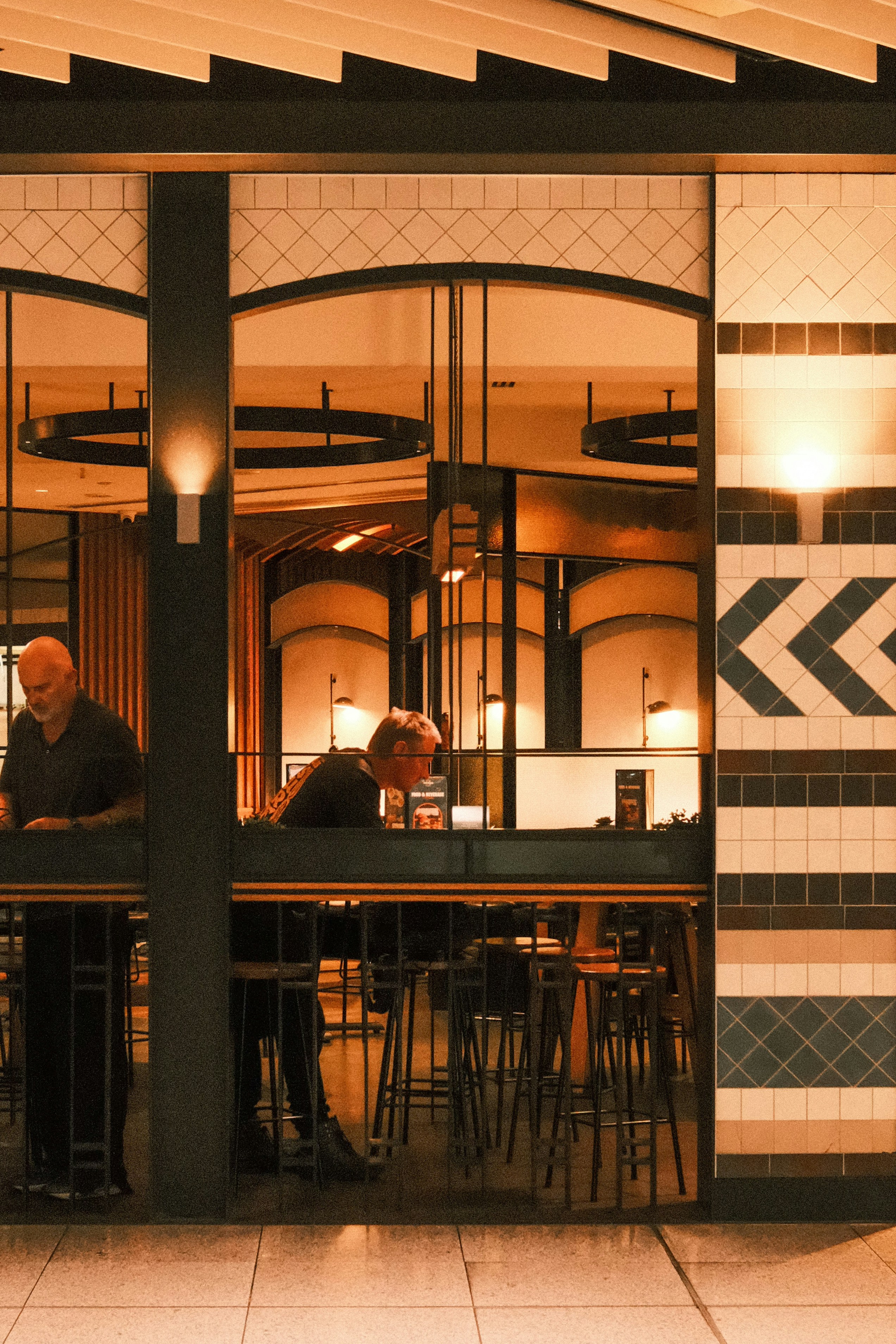 Deux hommes debout au comptoir d’un bar dans un café.