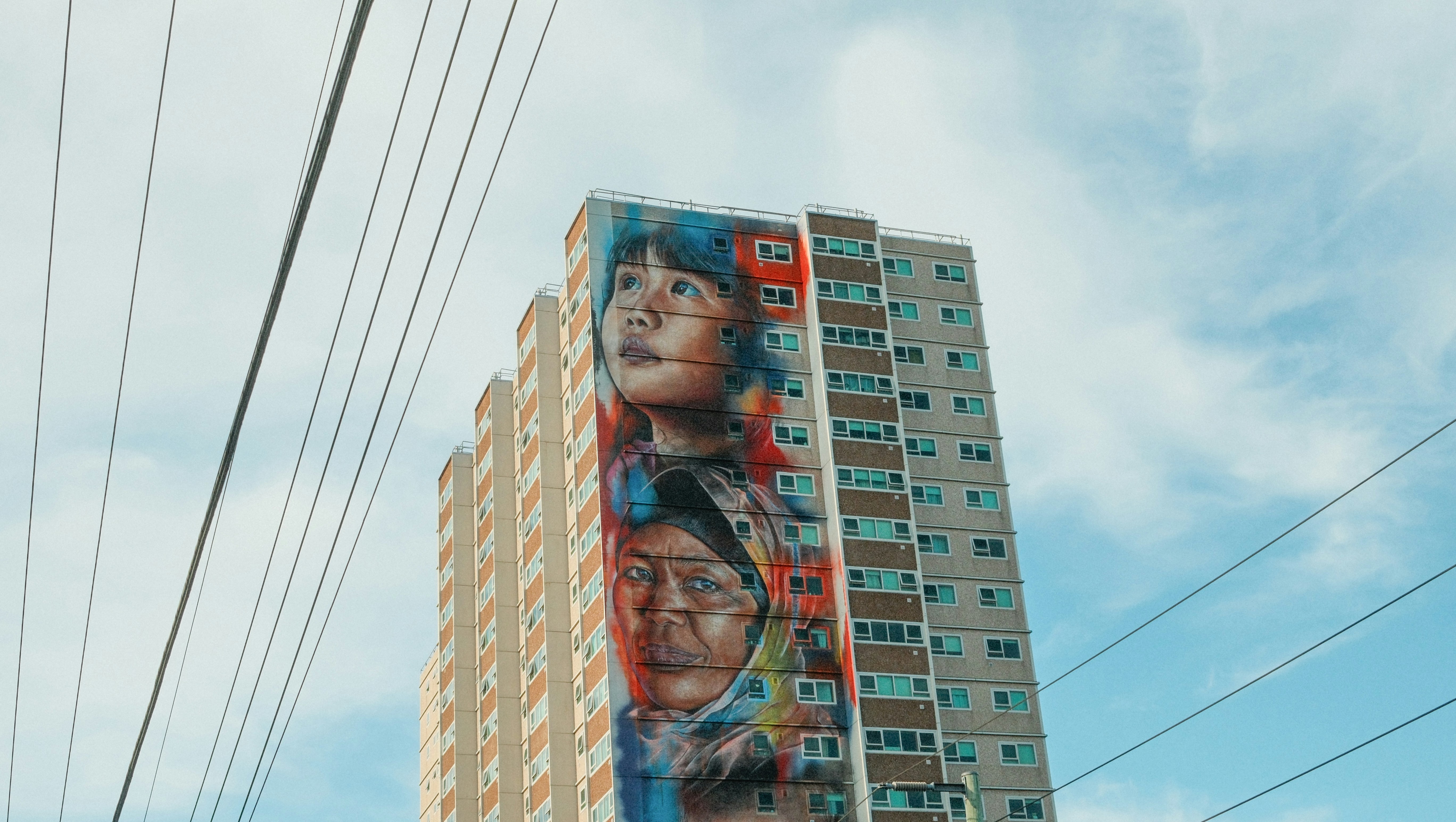 Art graffiti sur un grand immeuble sous un ciel nuageux.