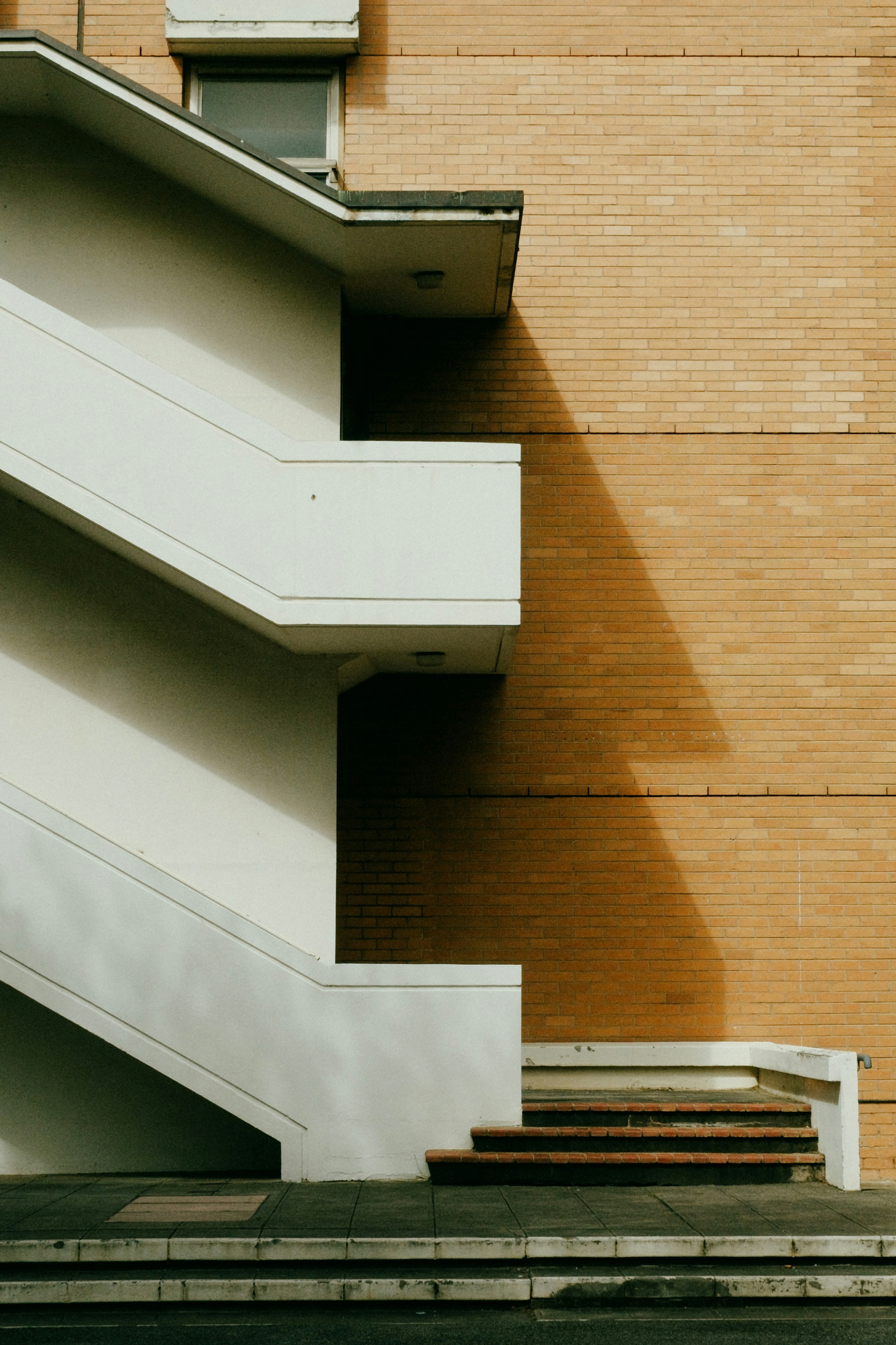 White staircase against a brick building with shadow