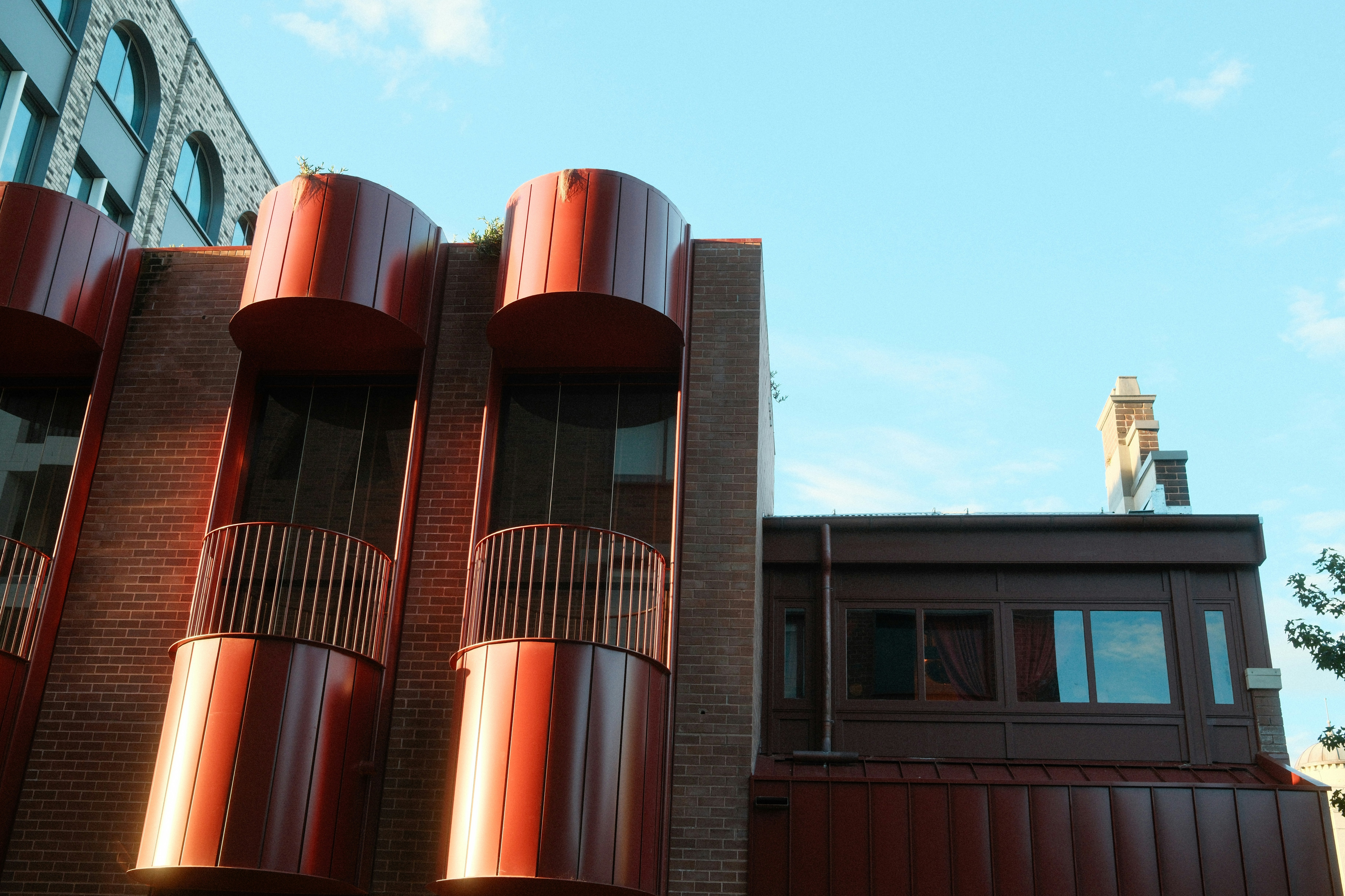 Bâtiment moderne avec des accents cylindriques rouges sur un ciel bleu