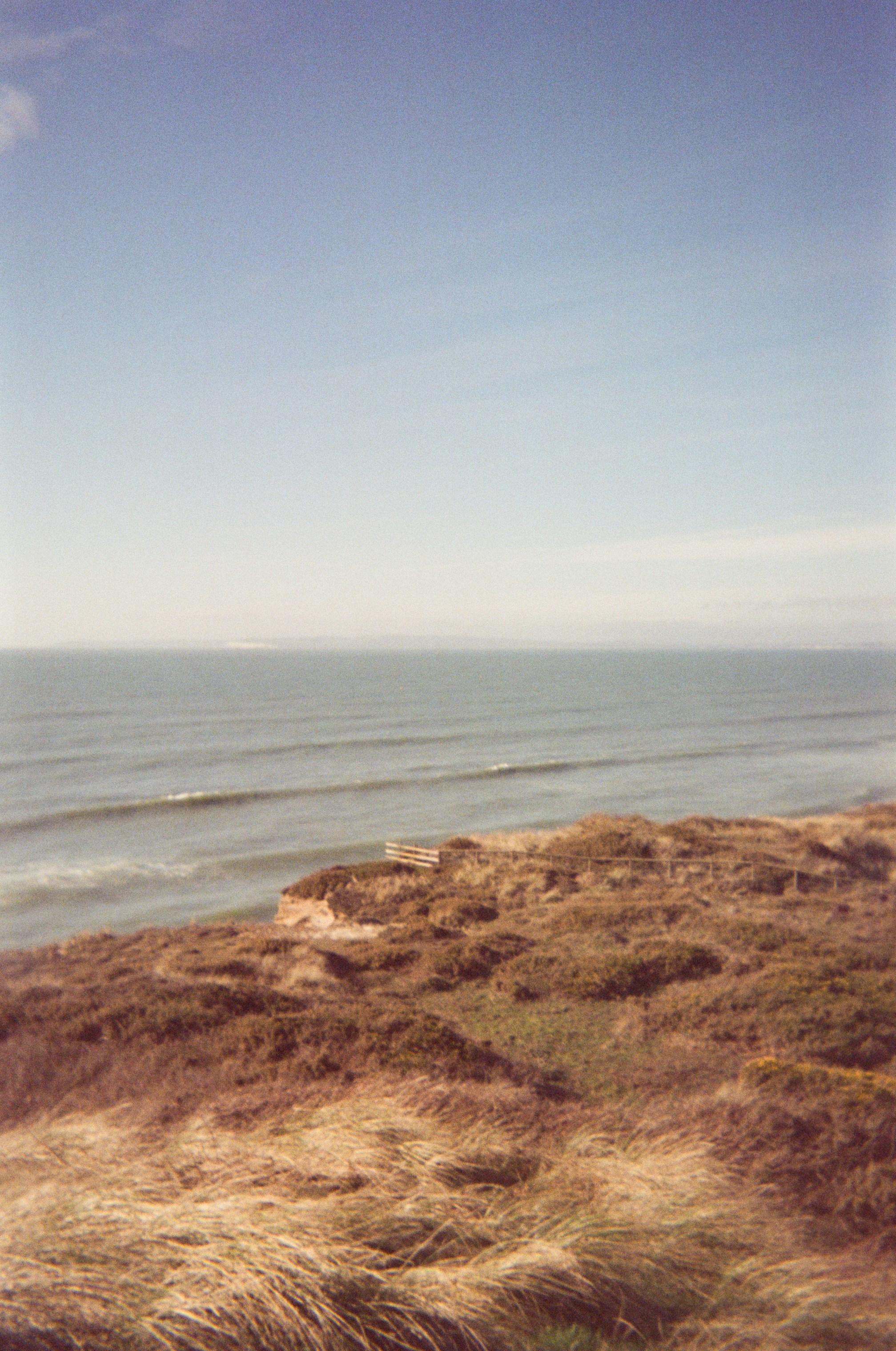 Ocean waves roll onto a grassy coastline undercliff.