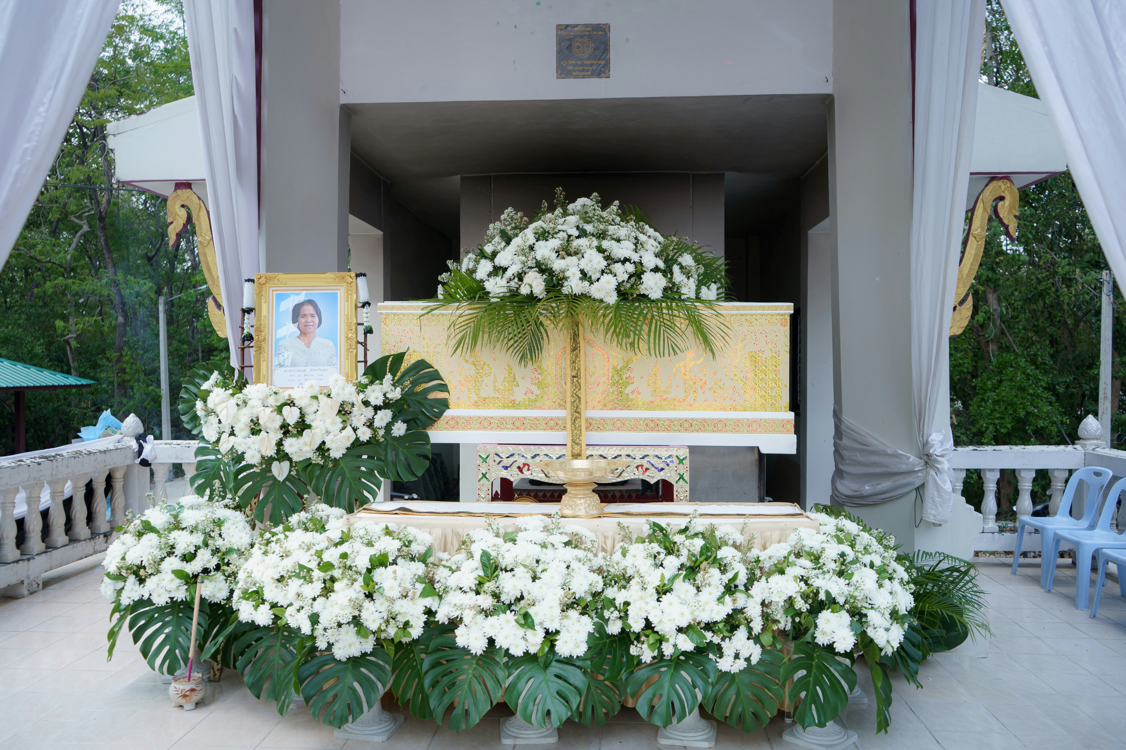 A funeral altar decorated with white flowers and a portrait.