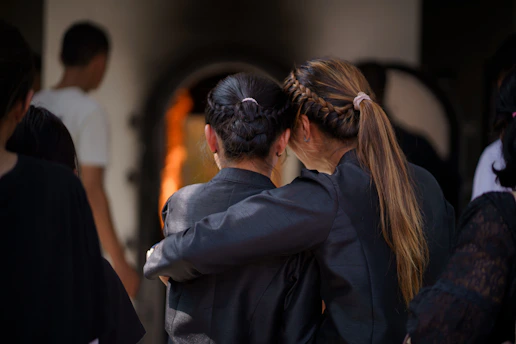 Two women embrace in front of a cremation furnace