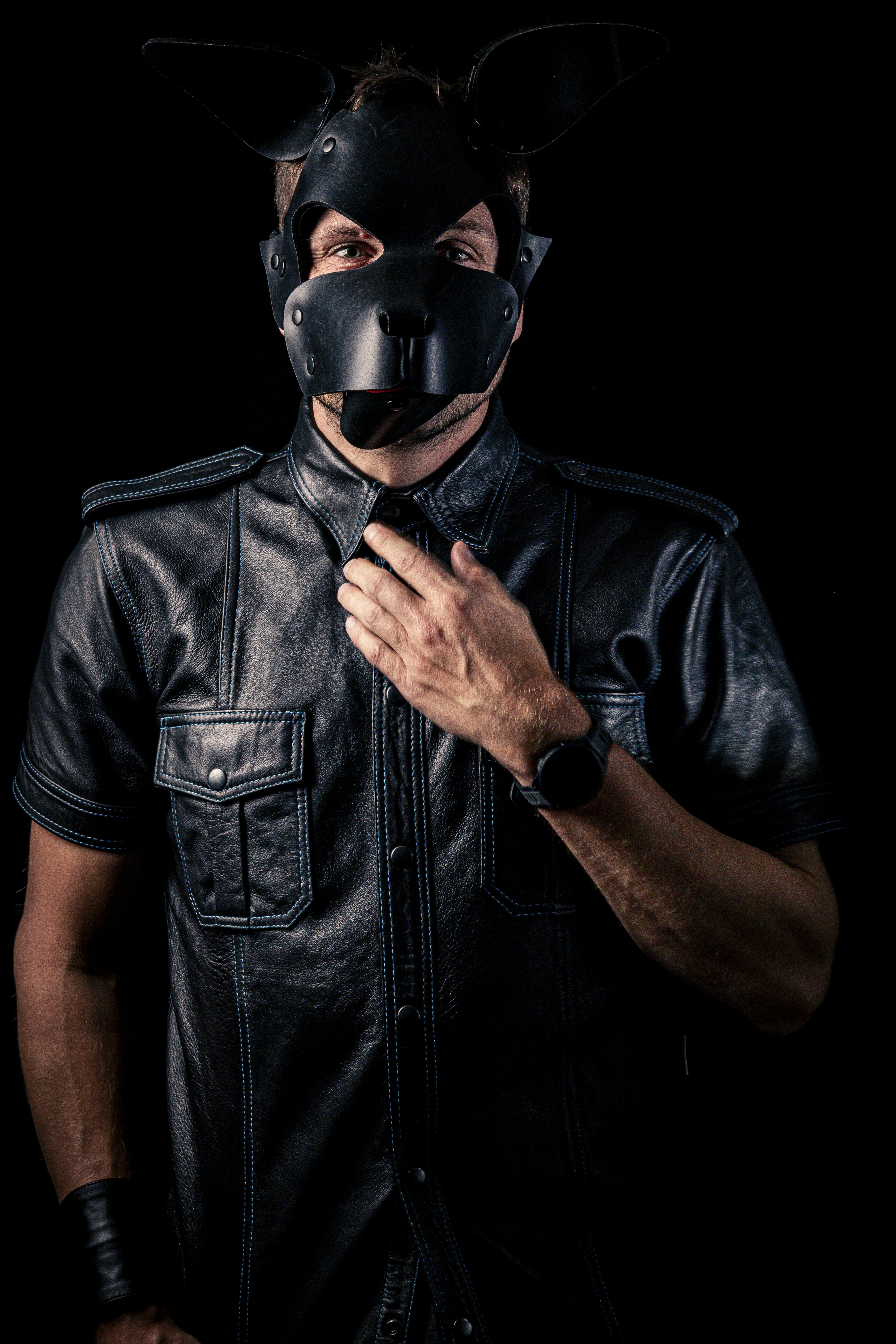 Un homme au masque et chemise en cuir ajuste le col de la chemise