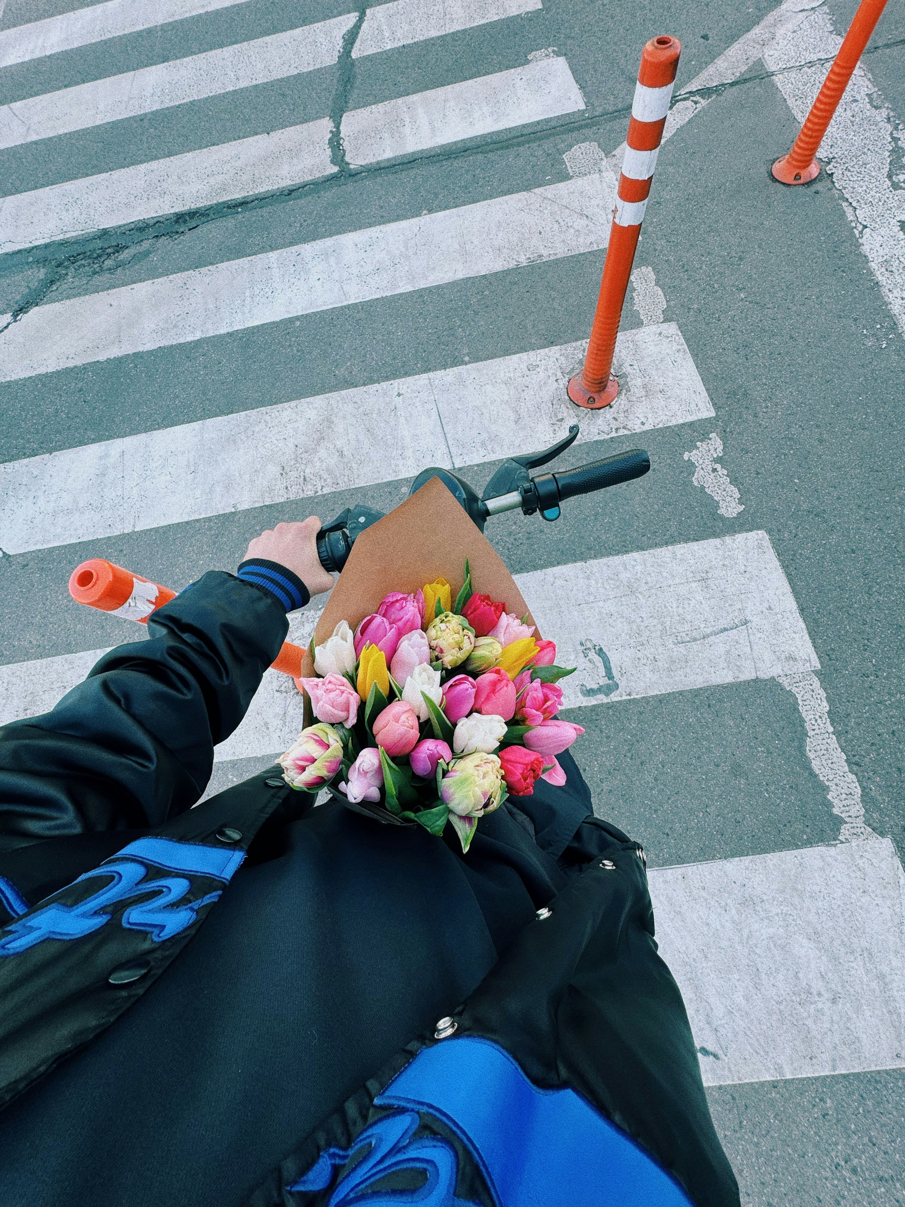 Persona in scooter che tiene un mazzo di tulipani