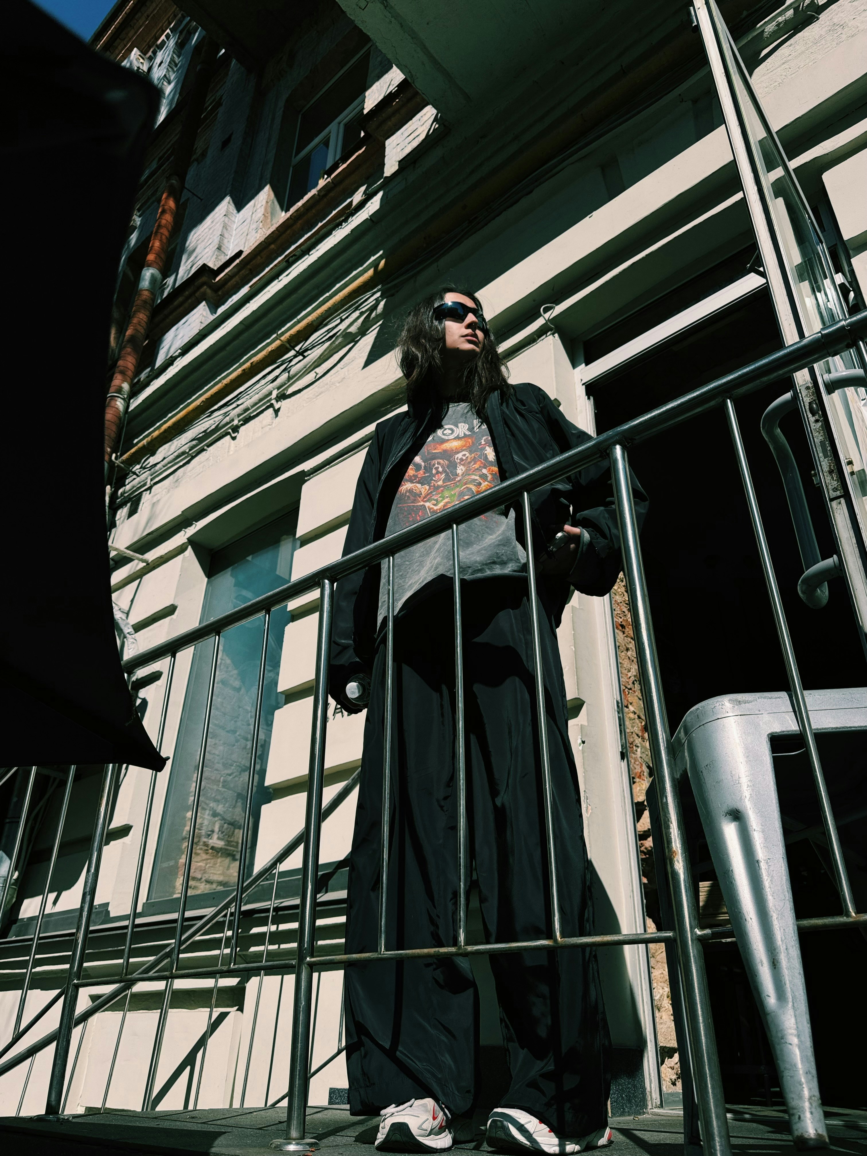 Una persona con gli occhiali da sole sta in piedi su un balcone.