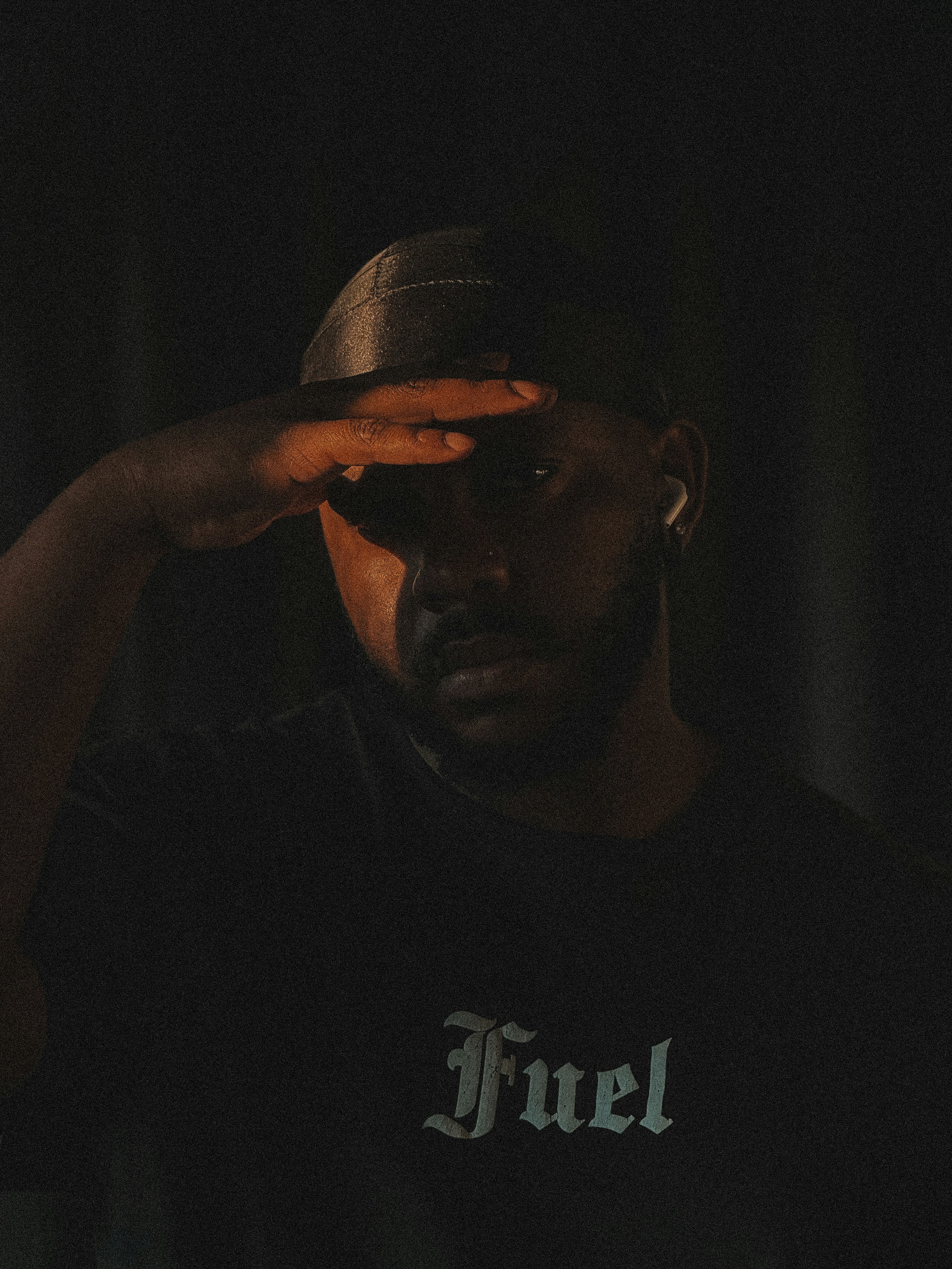 Man in dark shirt salutes with hand over eyes